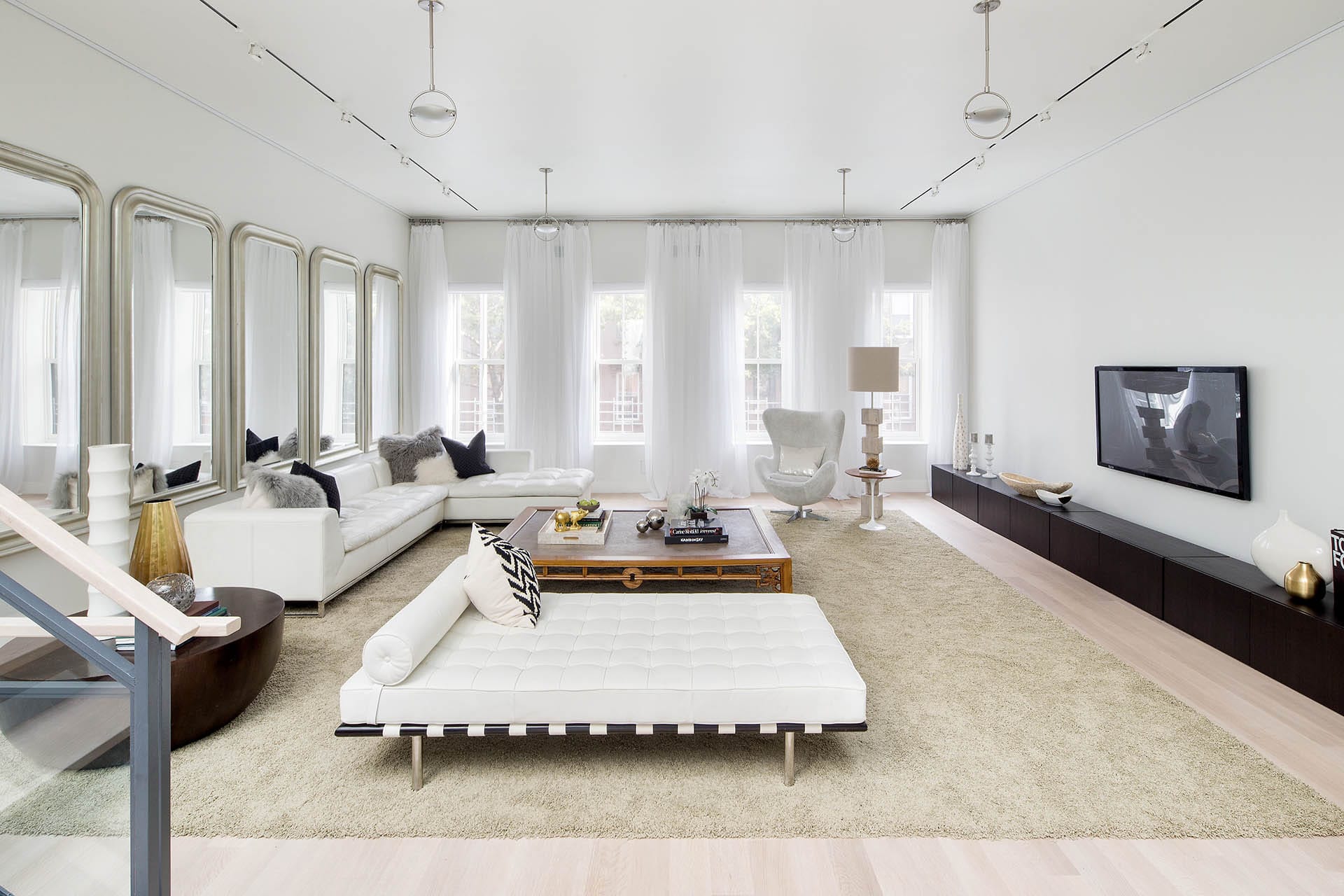 Neutral living room with white furniture and 5 large mirrors on the wall.