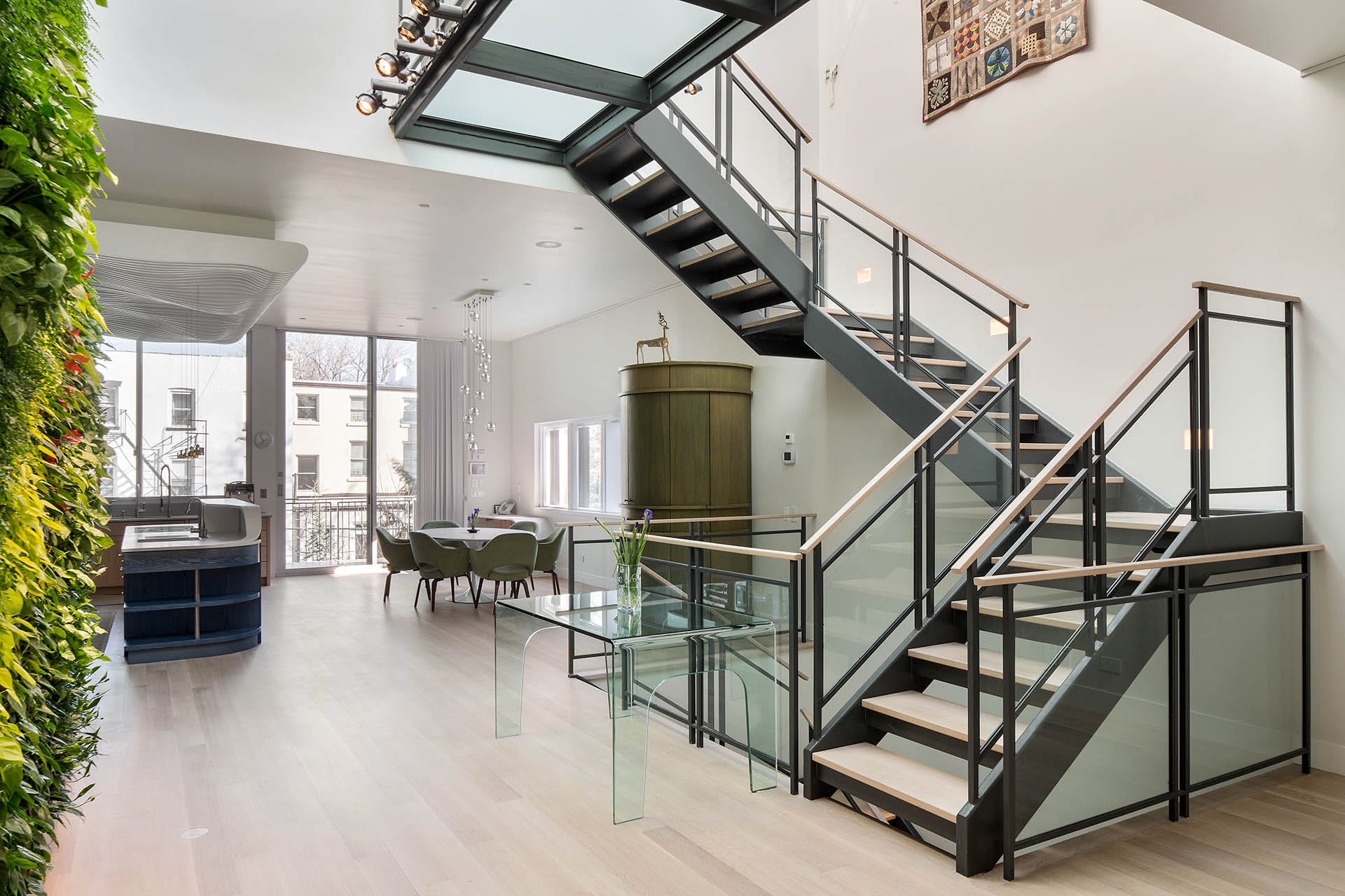 Open concept floating staircase leading to the kitchen with a wall of plants.