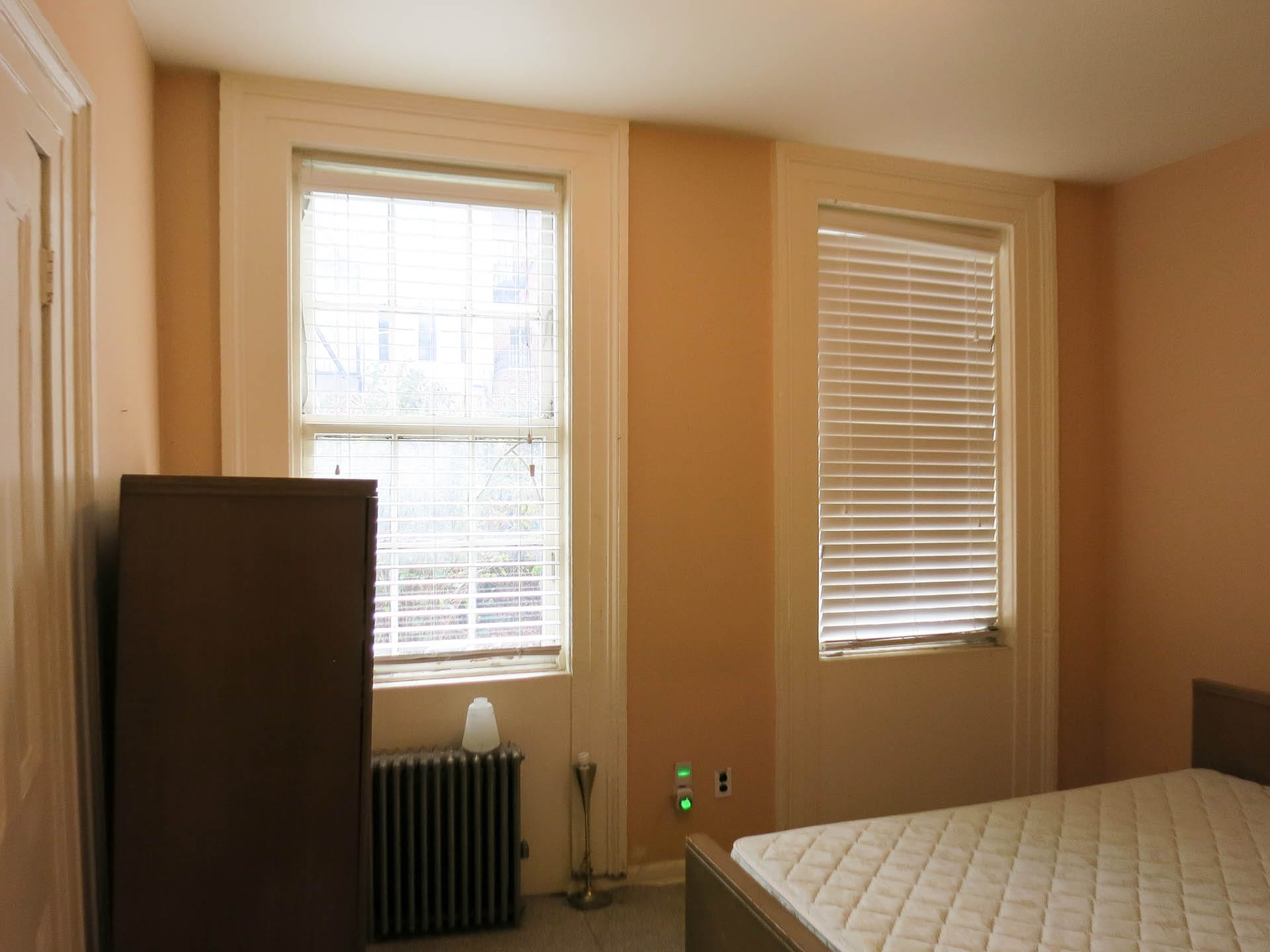 Bedroom with pink walls and two windows in a Brooklyn Heights Passive House before renovation.