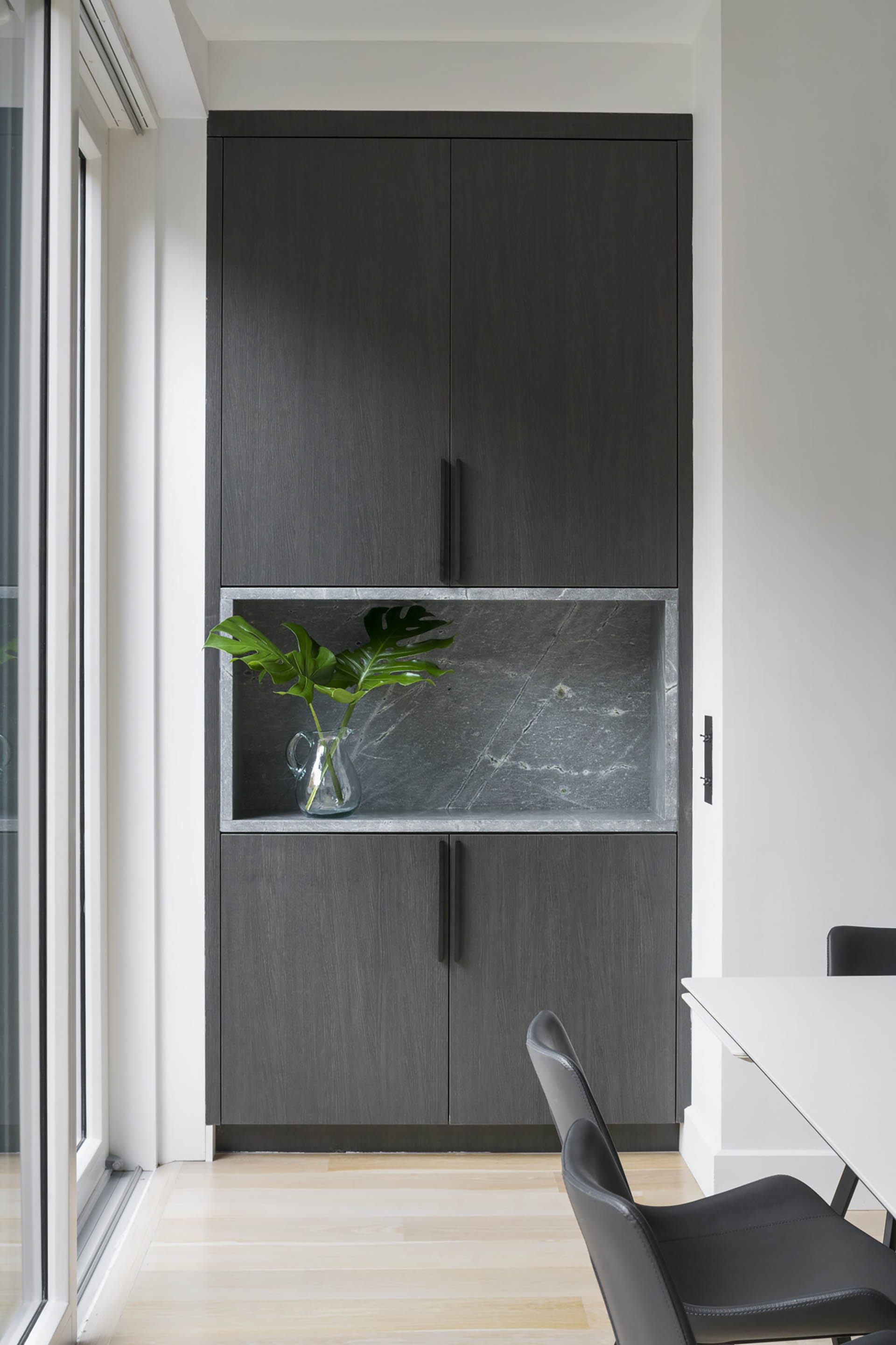 Wall of a dining room in a Brooklyn Heights Passive House with cabinets and a stone display niche.