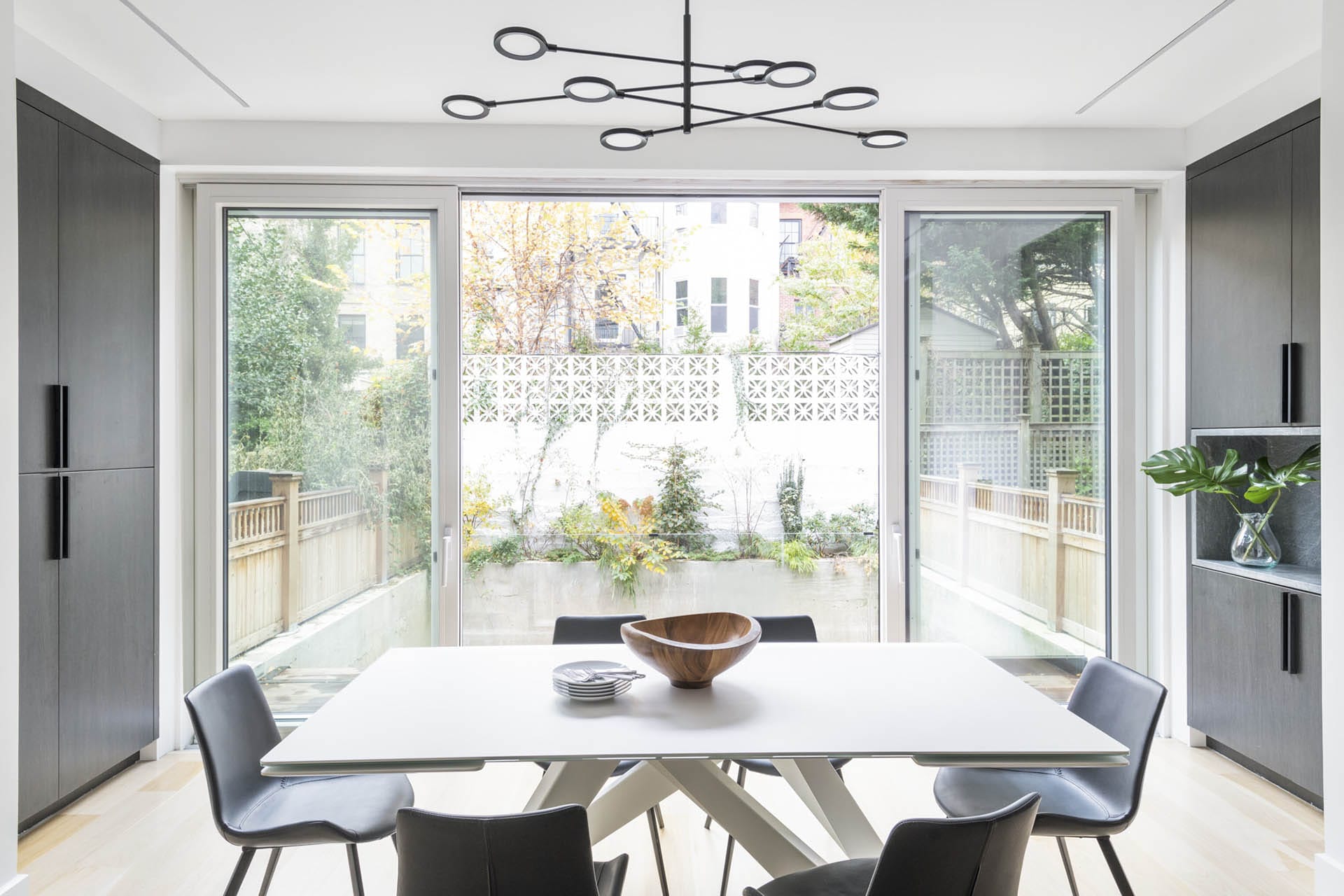 Parlor-level dining room with modern chandelier and floor to ceiling sliding glass doors leading out to back yard.