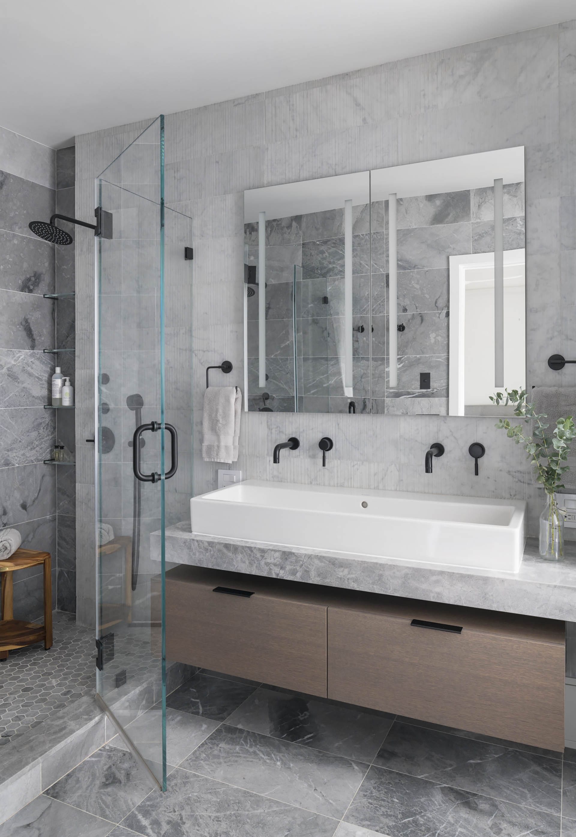 Shower stall and Jack-and-Jill vanity in a grey stone primary bathroom.