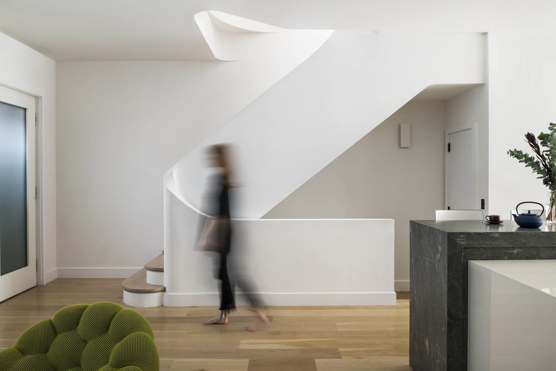 Woman walking in front of custom plaster staircase in a Brooklyn Heights Passive House
