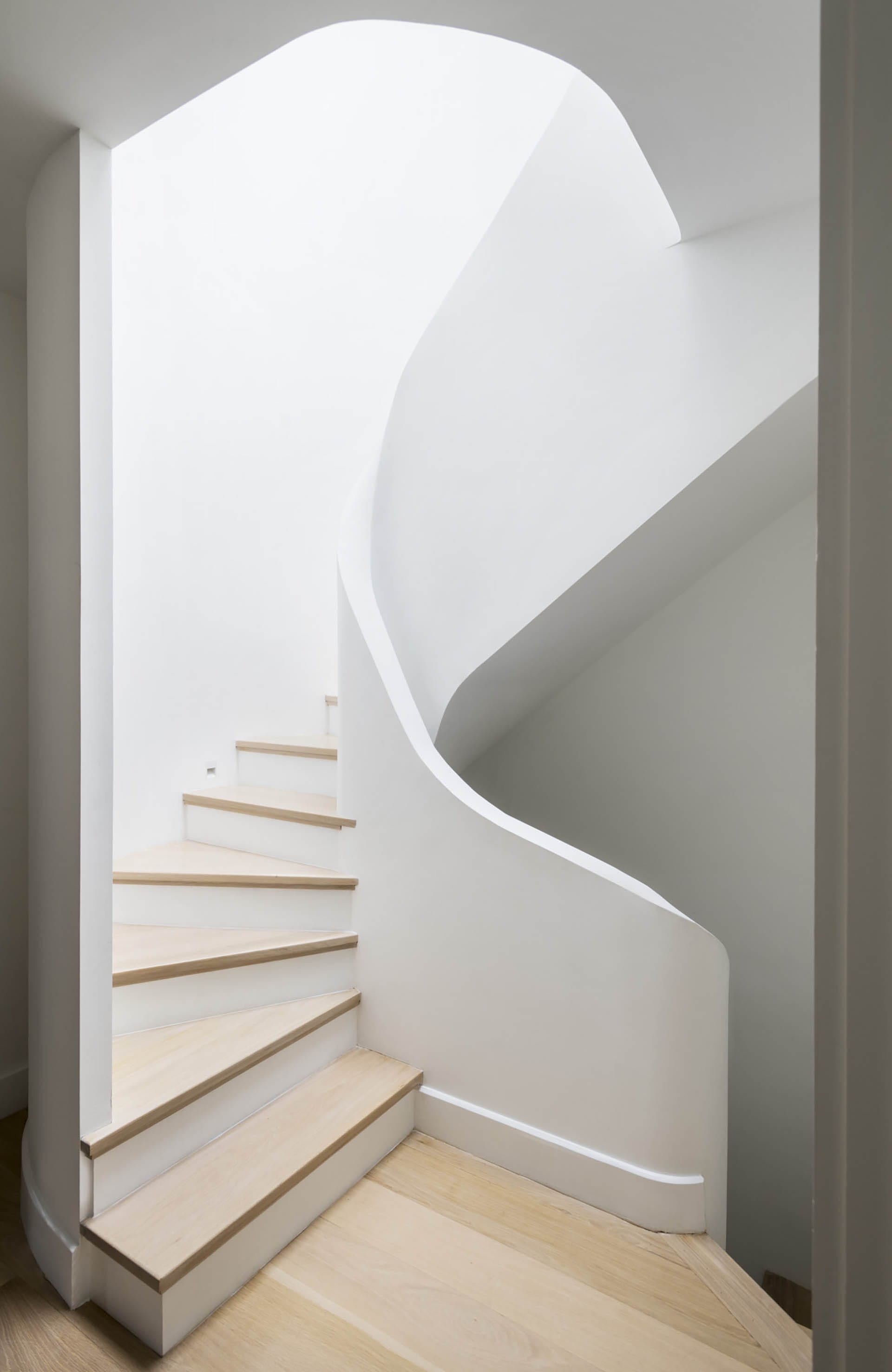 Custom, white plaster spiral staircase in a Brooklyn Heights Passive House