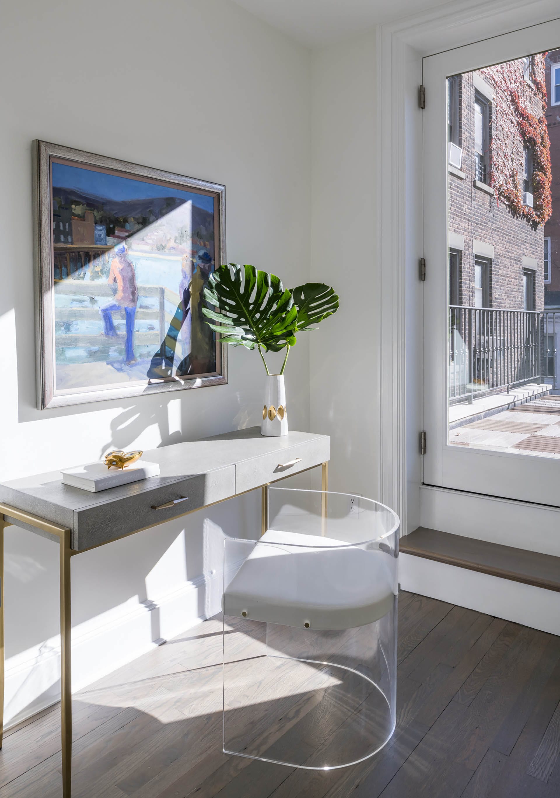 Office space with a clear acryllic chair, painting on the wall, and glazed door leading to a roof deck.