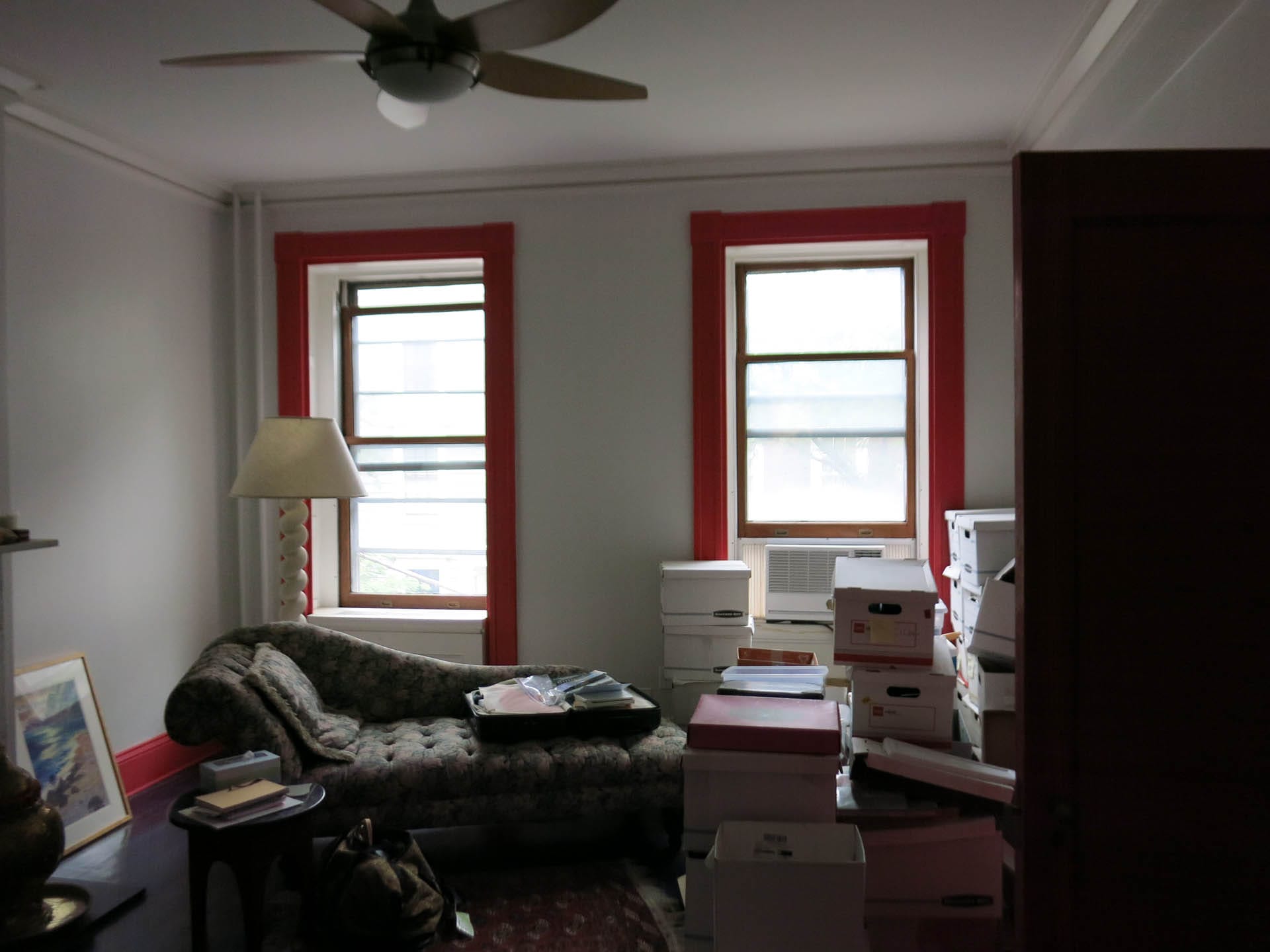 Primary bedroom before renovation with red trim around the windows and floors and white walls.