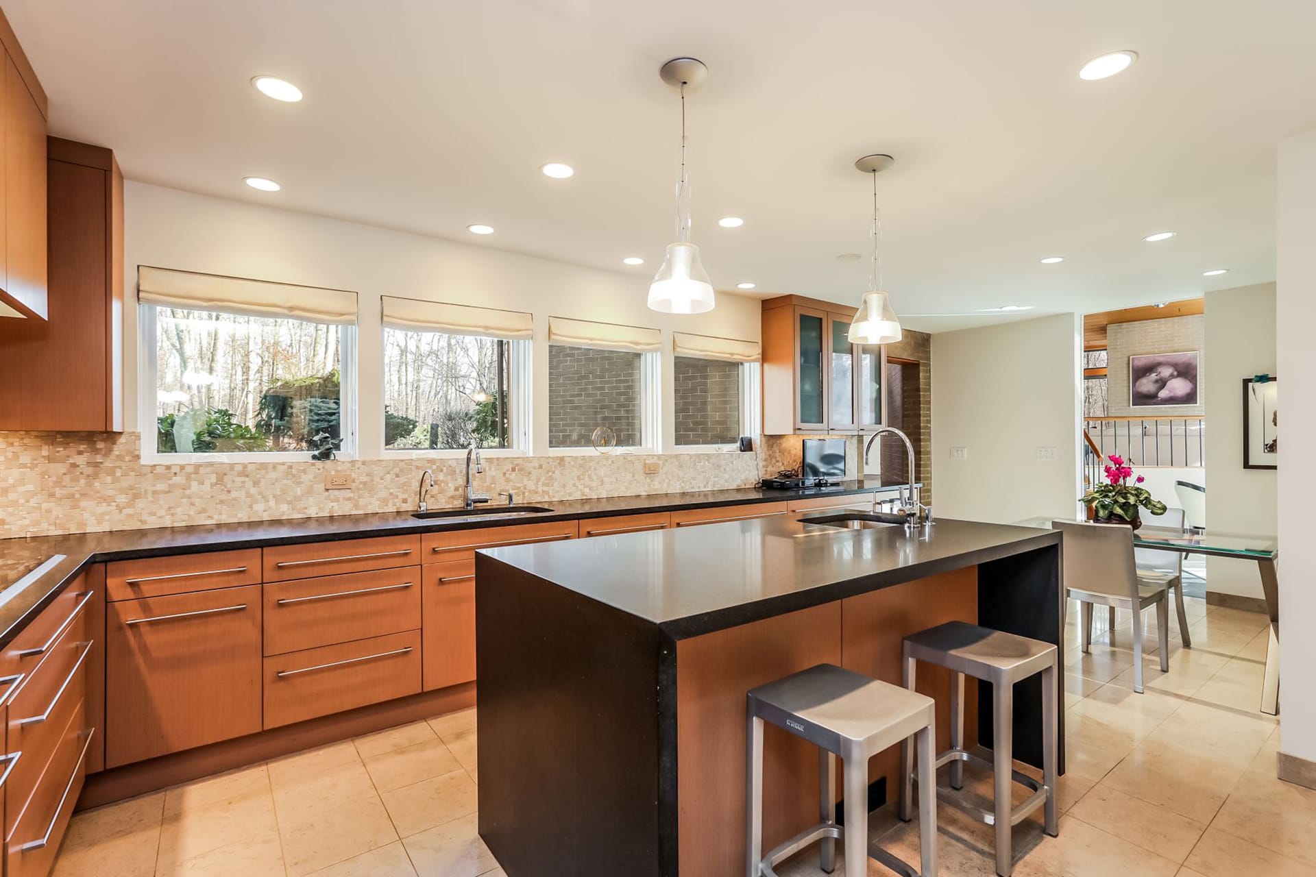 Kitchen with two pendant lights, black countertops, and a wood and black island