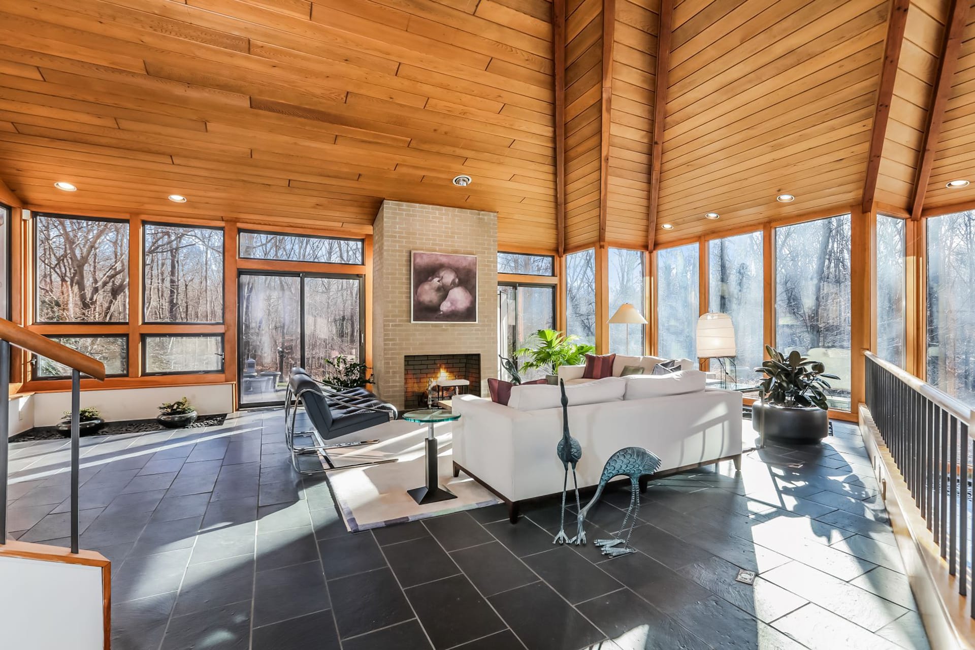 Living room with slate floors, a brick fireplace, and wood paneled ceilings