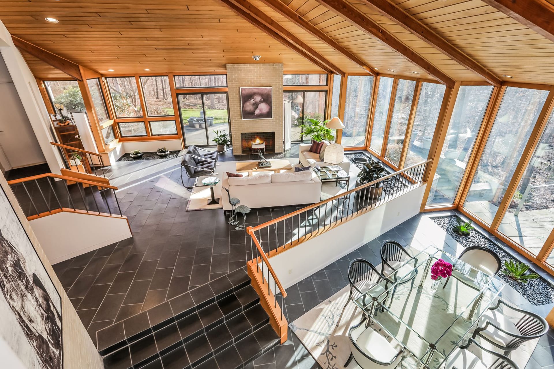 Living space with floor to ceiling windows, wood paneled ceilings, and slate floors.