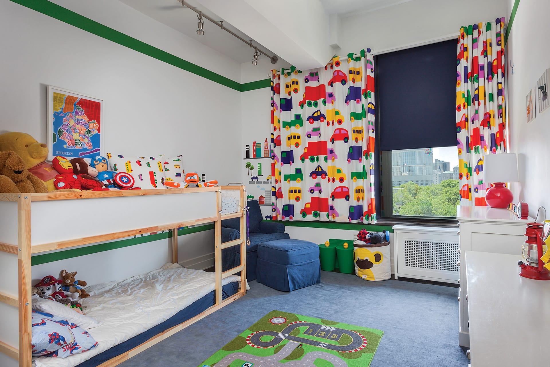 Kids room with bunk beds, blue carpet, car-print curtains, and a row of toys on top of the bed.