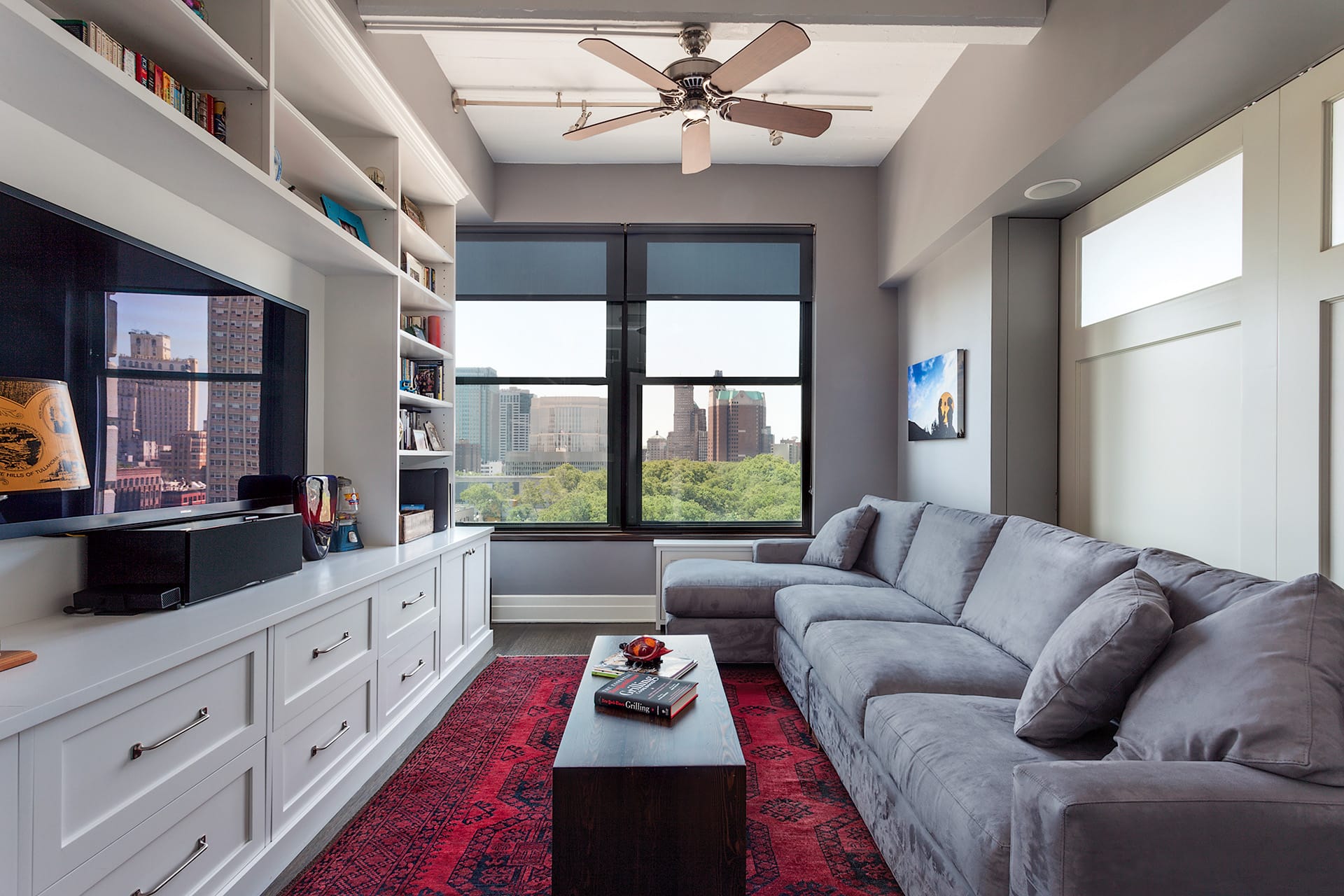 Entertainment room with a large grey couch, red area rug, and large pocket doors separating the space from the living room