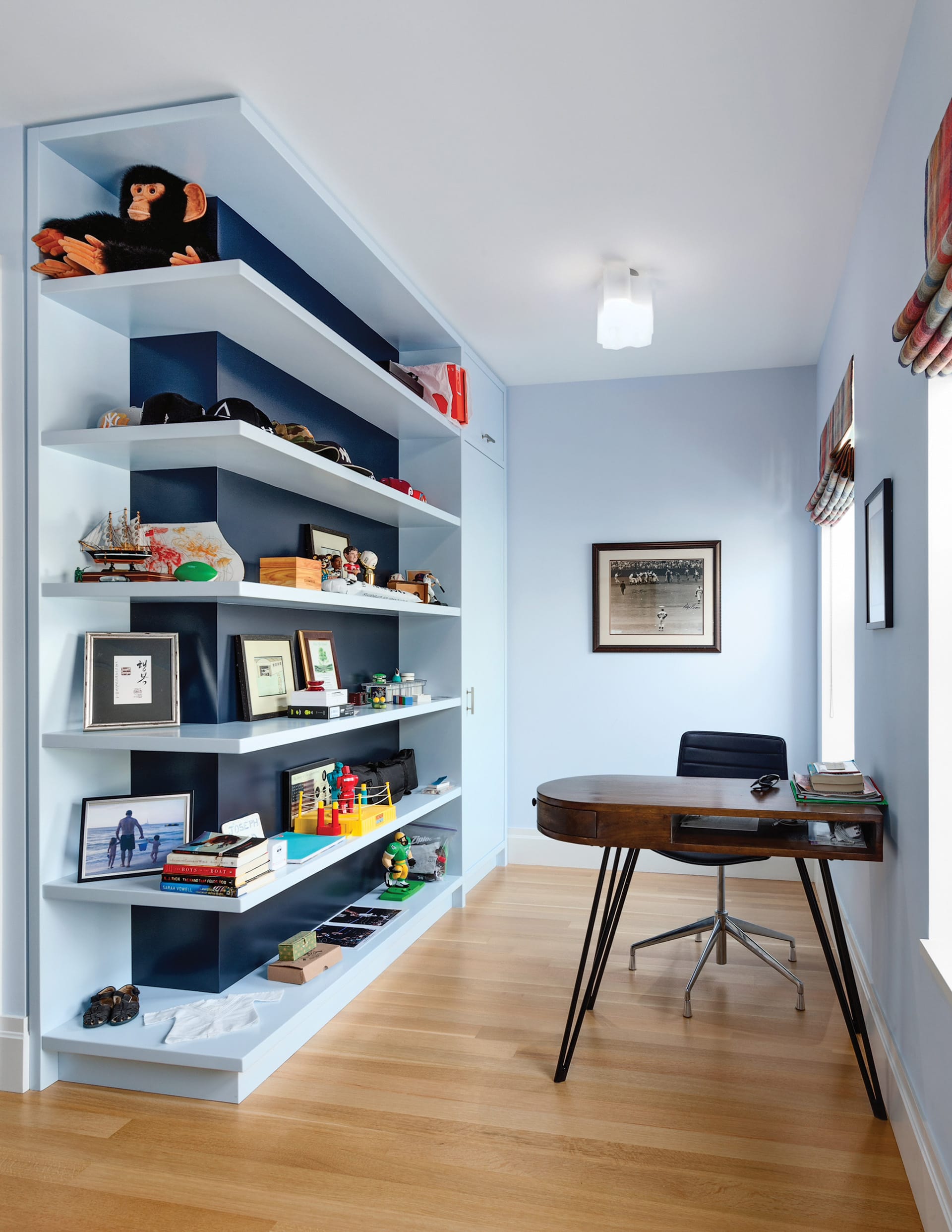 Desk in a child's bedroom with light blue walls and built-in shelving.