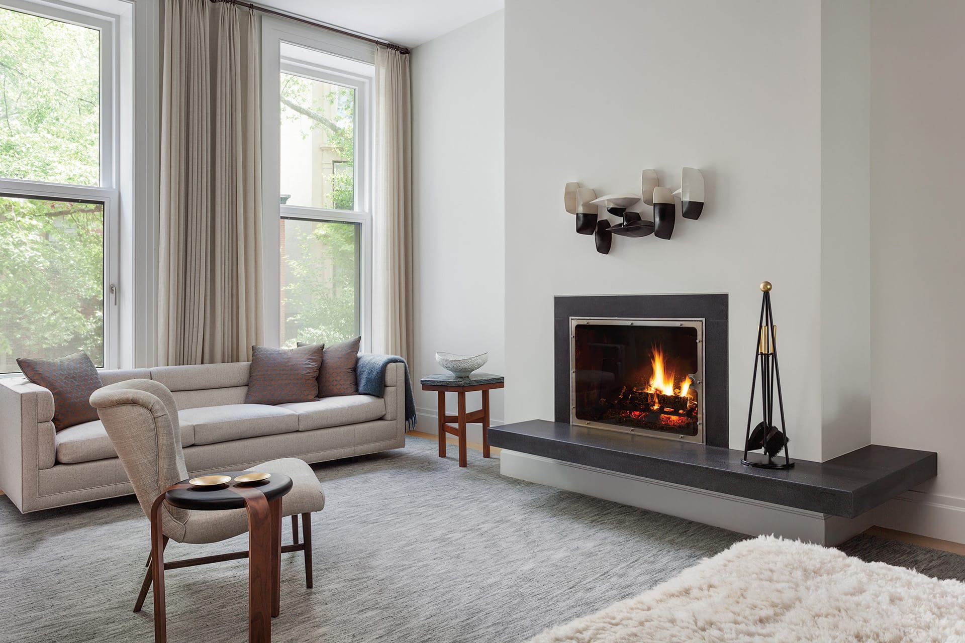 Den with grey carpet, fireplace, couch, and armchair in a Brooklyn Heights Passive House
