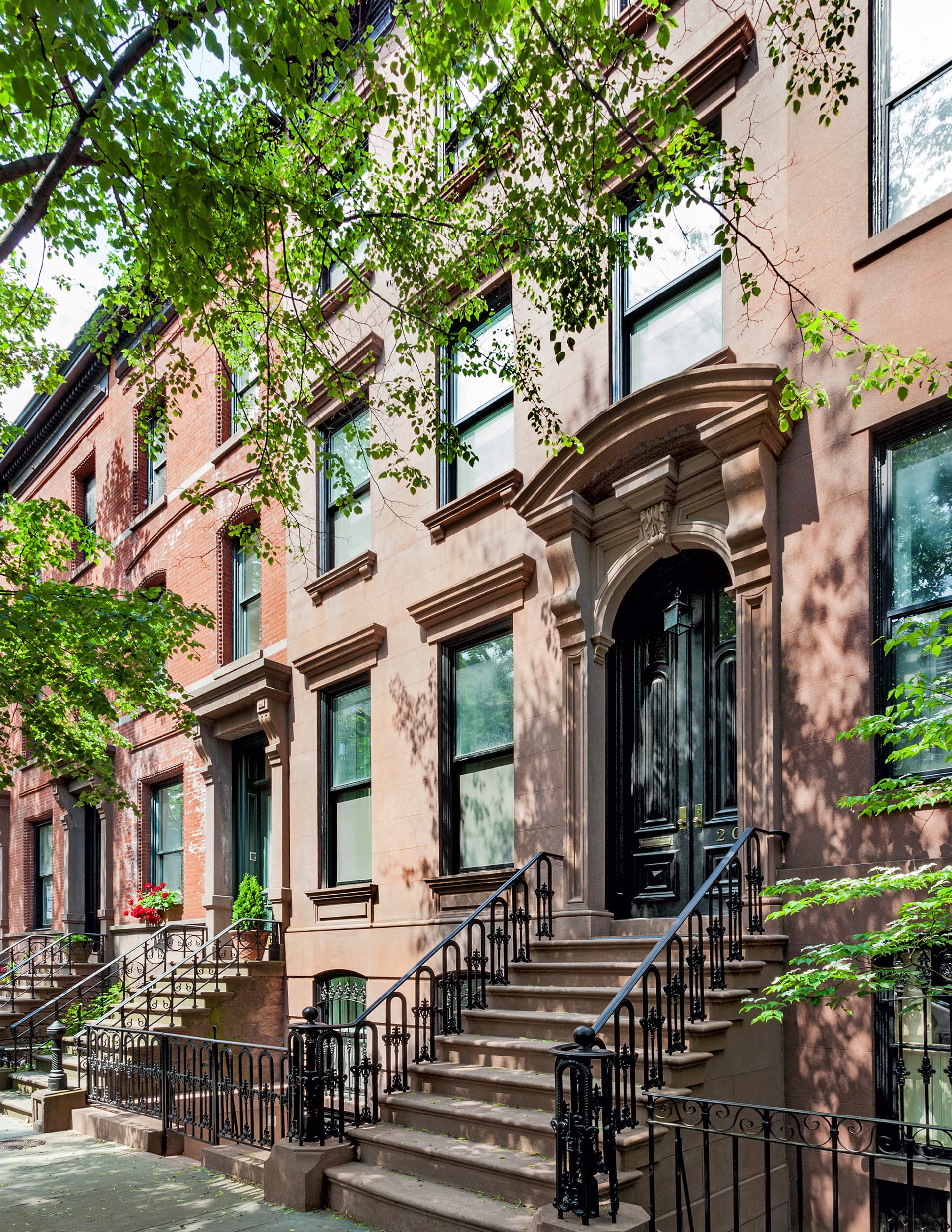 Restored front facade of a historic Brooklyn Heights brownstone with black front doors, a stoop, and ironwork railings.