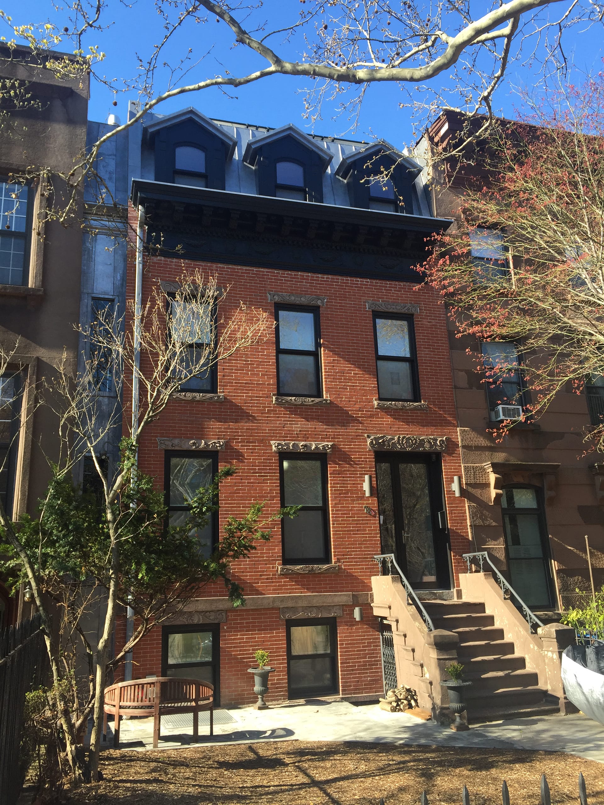 Front facade of a brick Carroll Gardens Passive house with carved brownstone lintels.