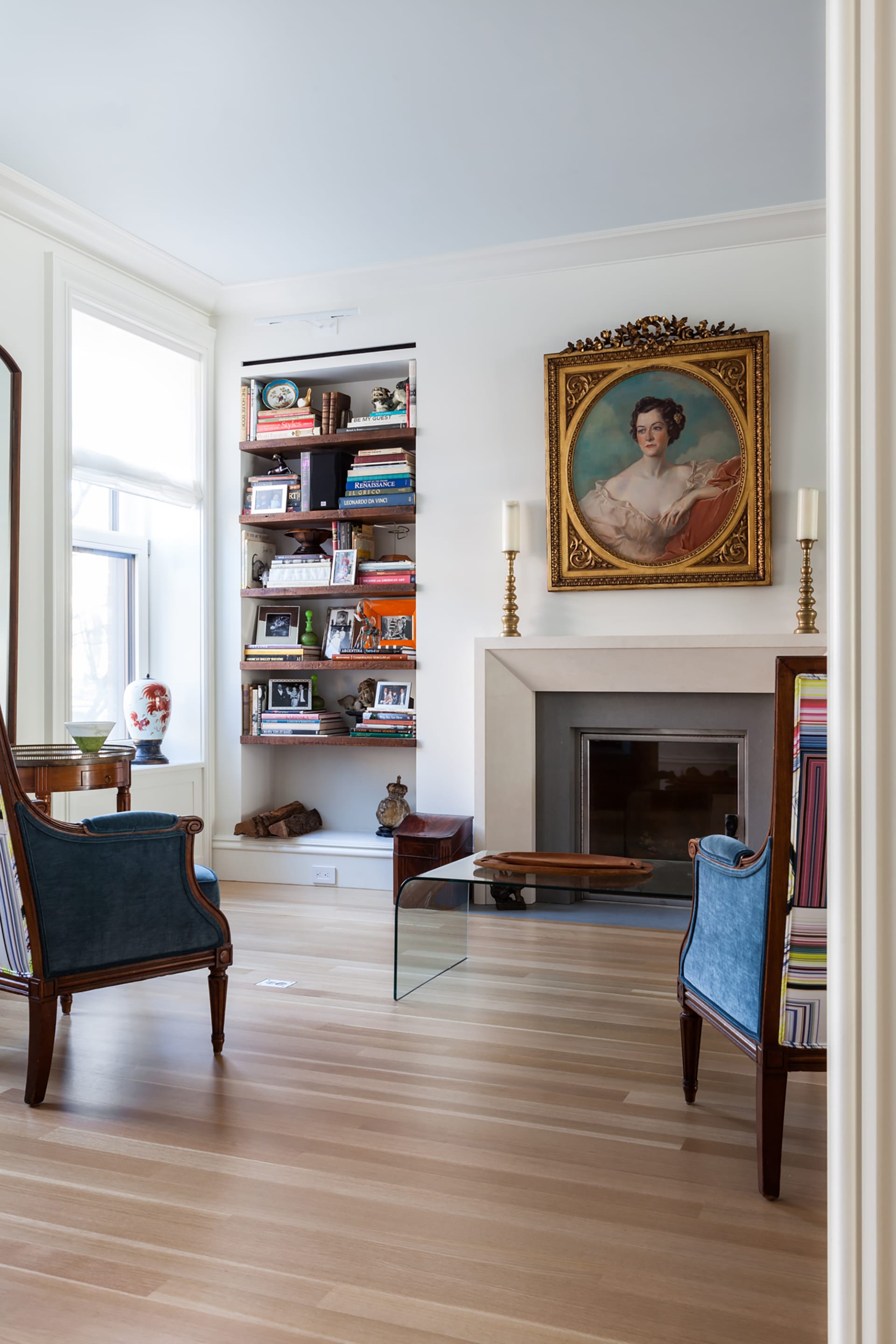 Parlor with built-in bookshelf and a large portrait of a woman in a gold frame.