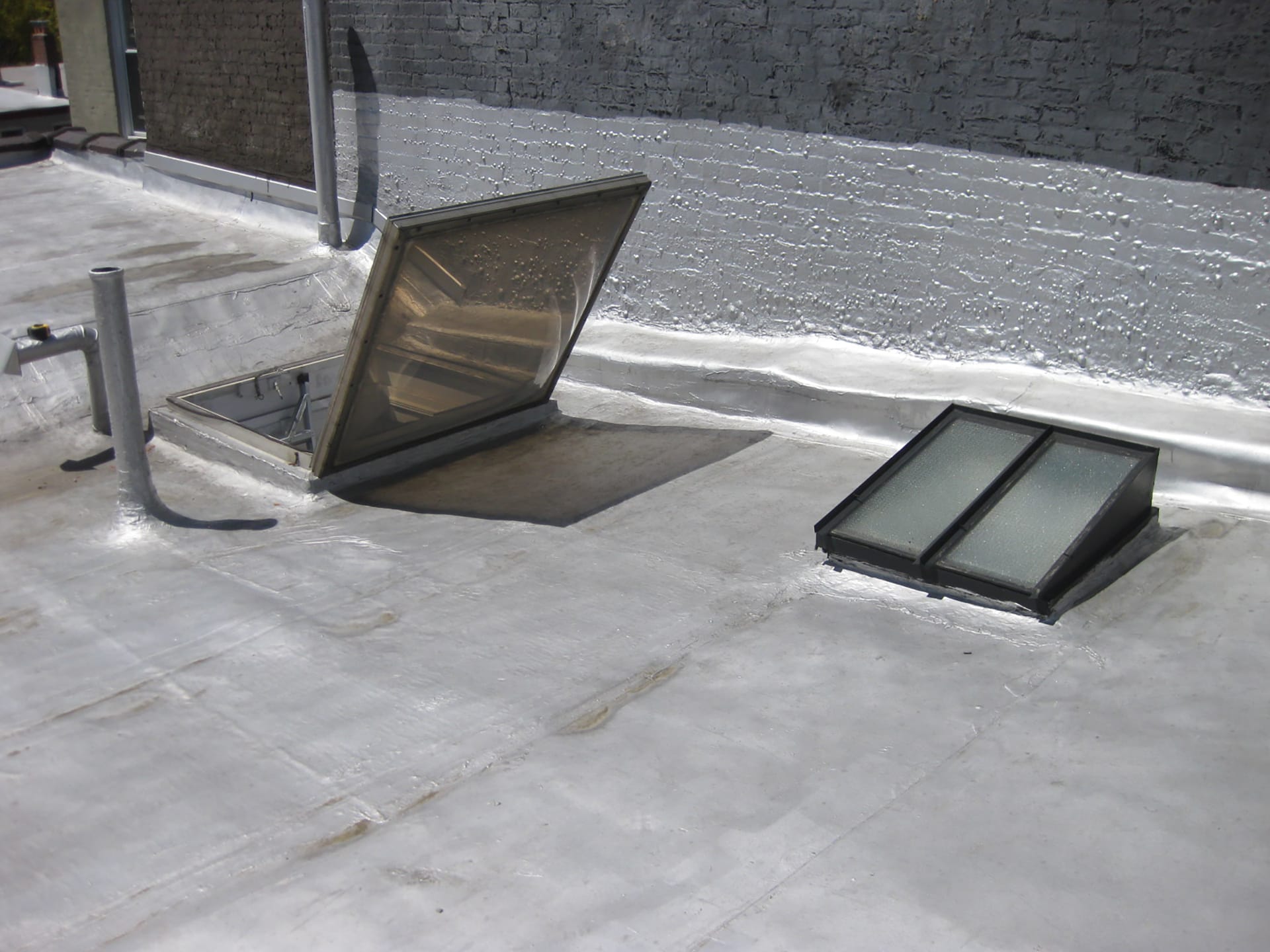 Carroll Gardens rooftop with a hatch leading to the attic, a skylight, and shiny reflective surface covering the roof.