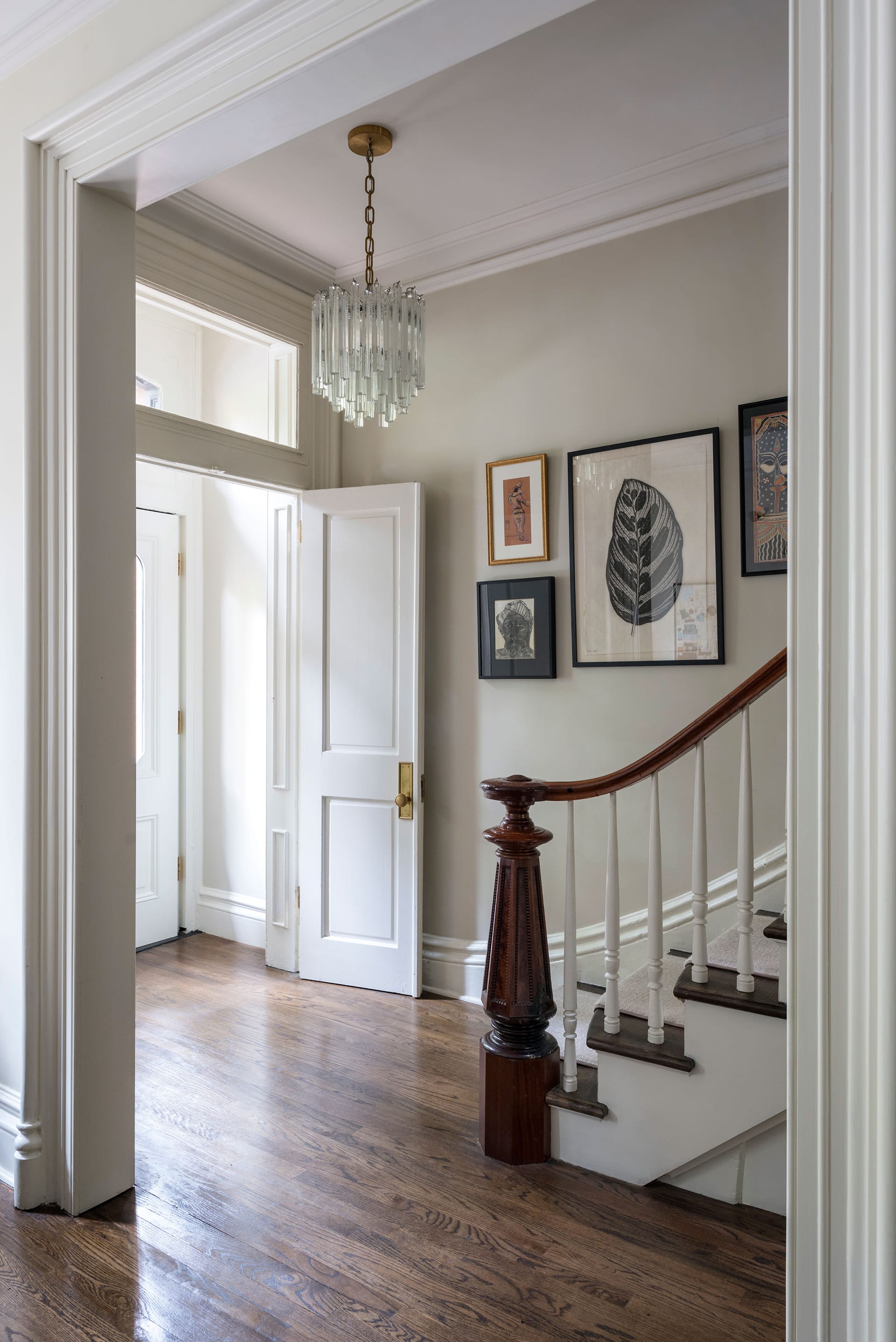 Foyer with wood floors, dark newel post, and chandelier