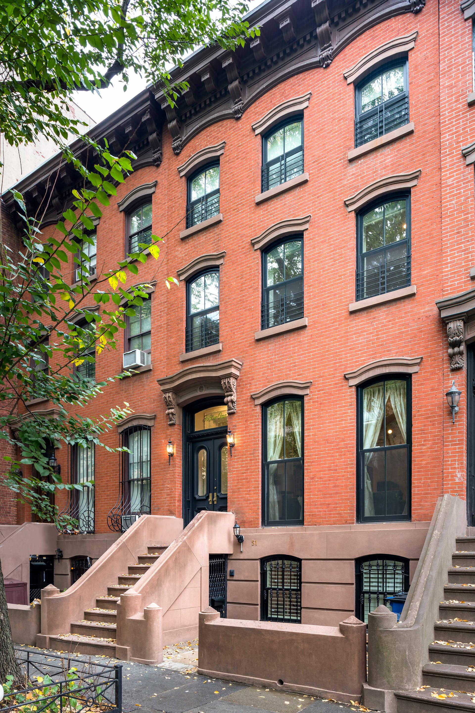 Front facade of a brick townhouse with a brownstone stoop in Fort Green, Brooklyn