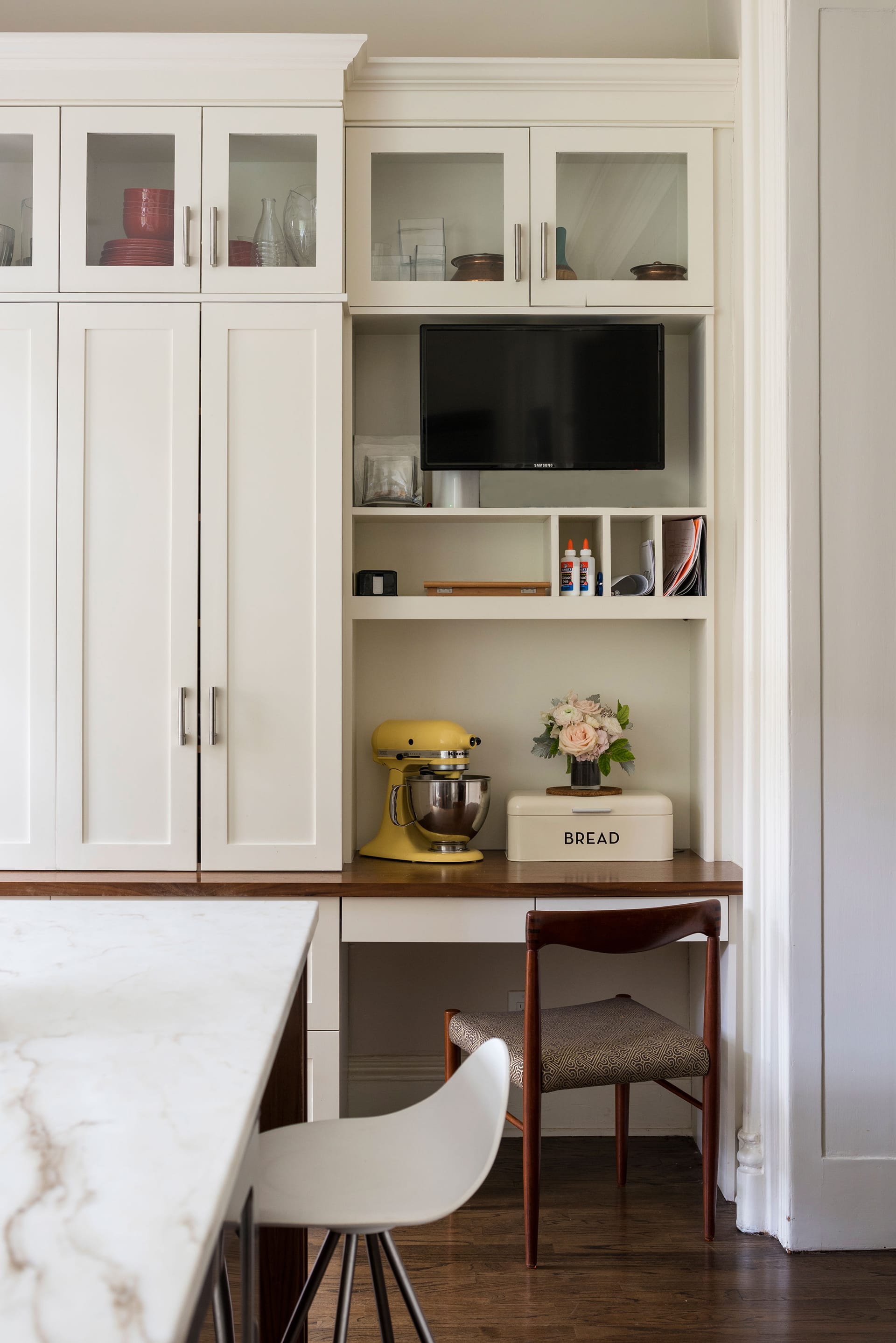 White millwork cabinetry with a small desk, marble island, and white barstool