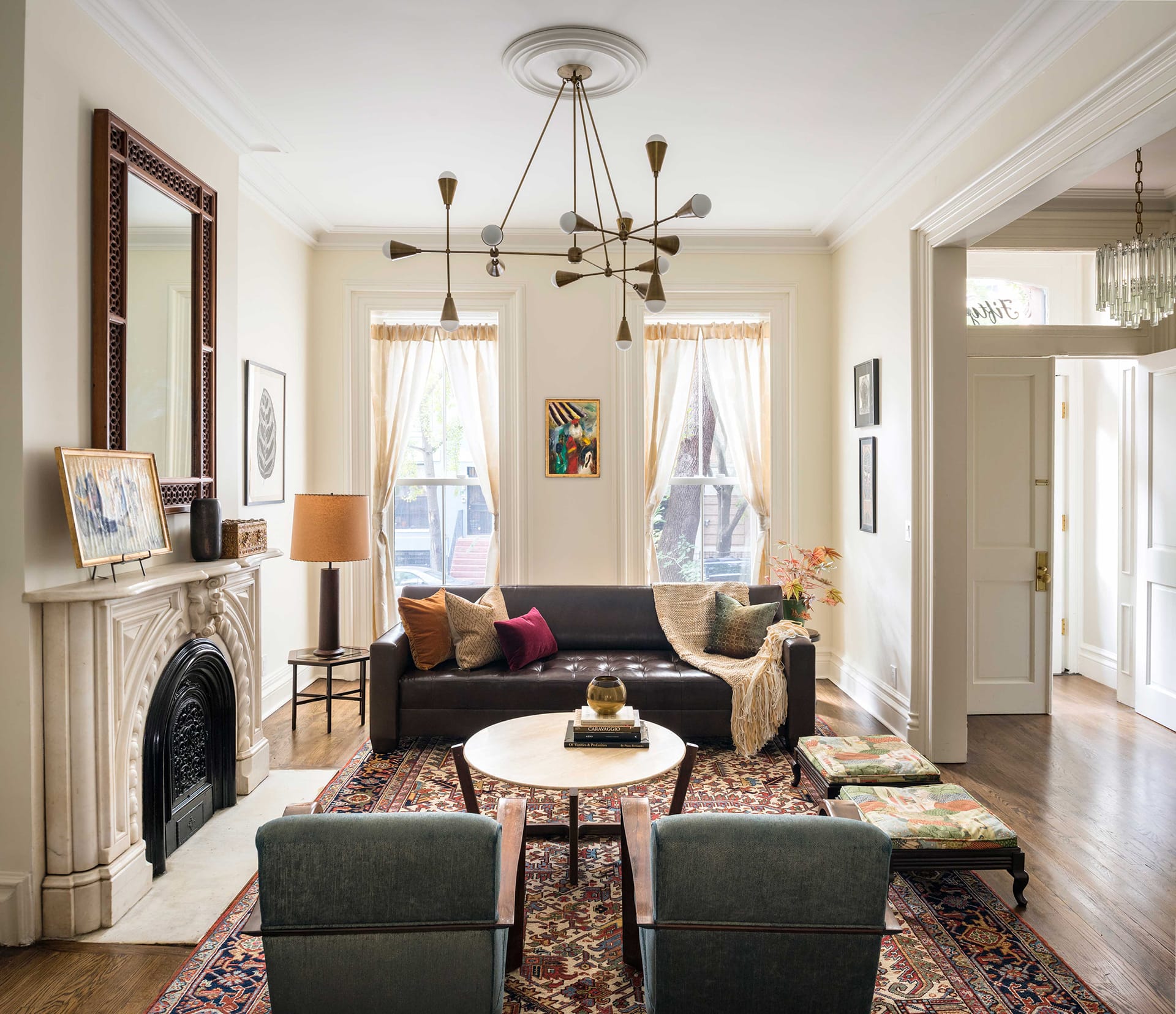 Living room with a couch and two armchairs, historic fireplace, and modern chandelier