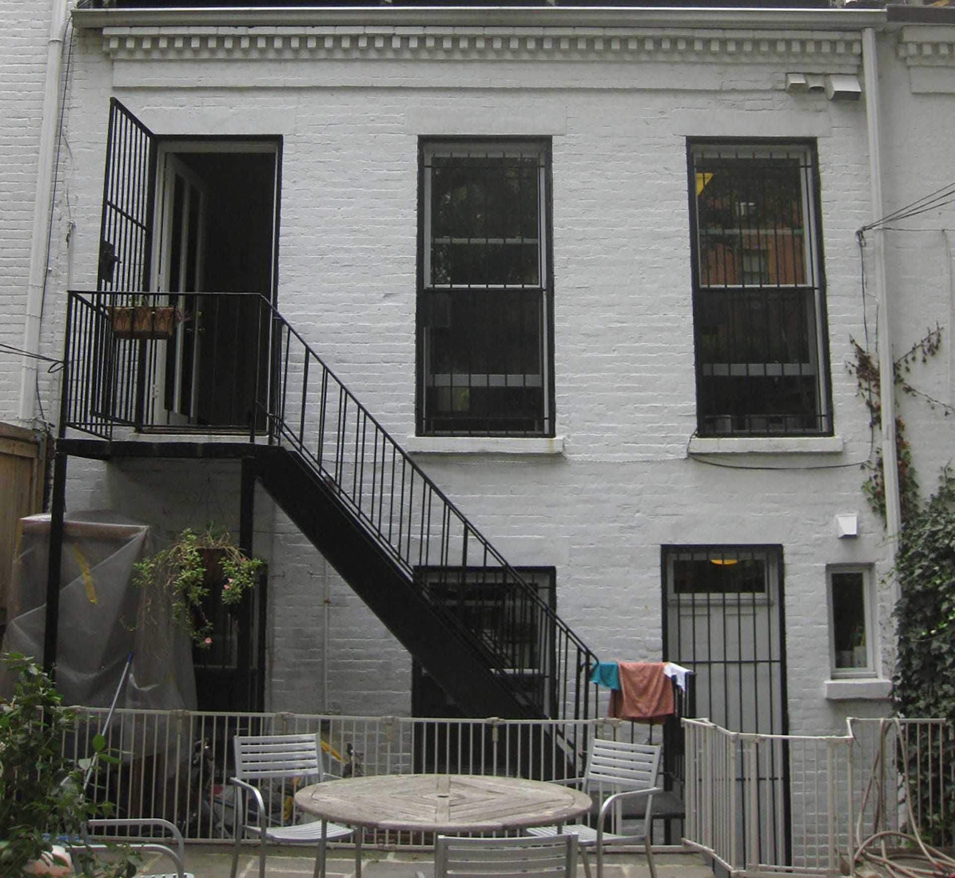 White-painted brick rear facade with bars over the windows and doors before our renovation