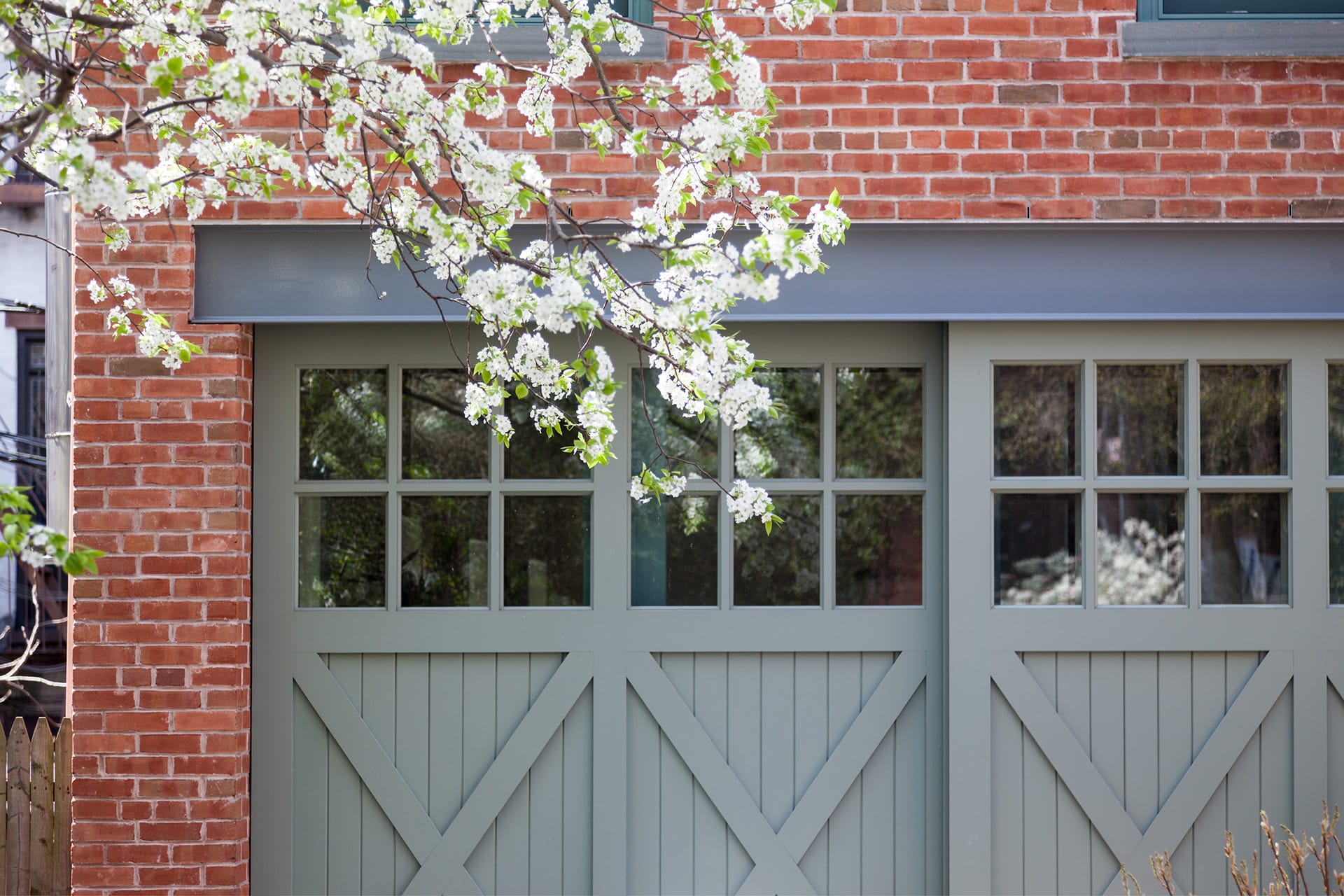 Close up of the green barn doors of a freestanding brick carriage house in Cobble Hill