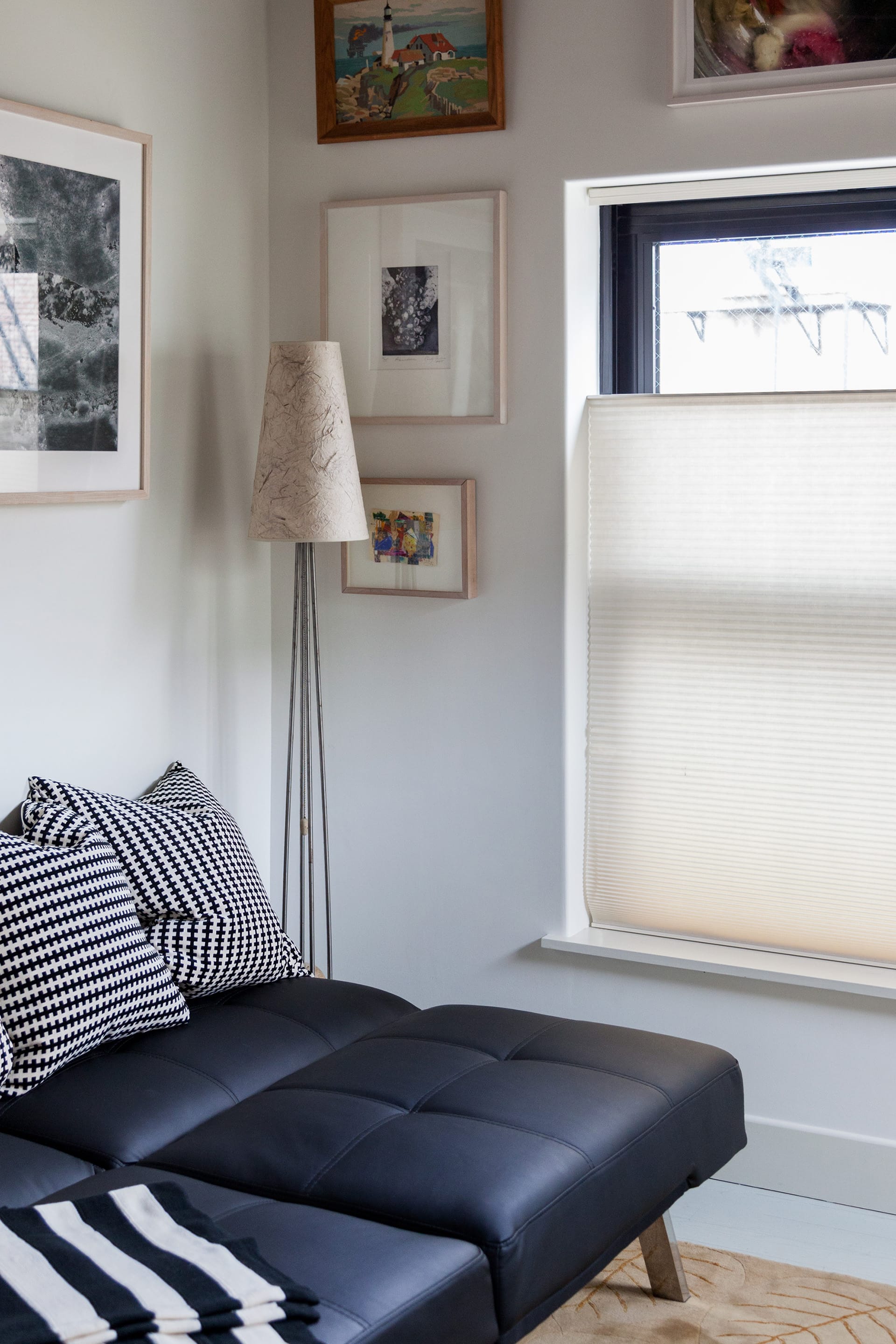 Black leather futon in a guest room of a Cobble Hill carriage house with a gallery wall of paintings and photographs