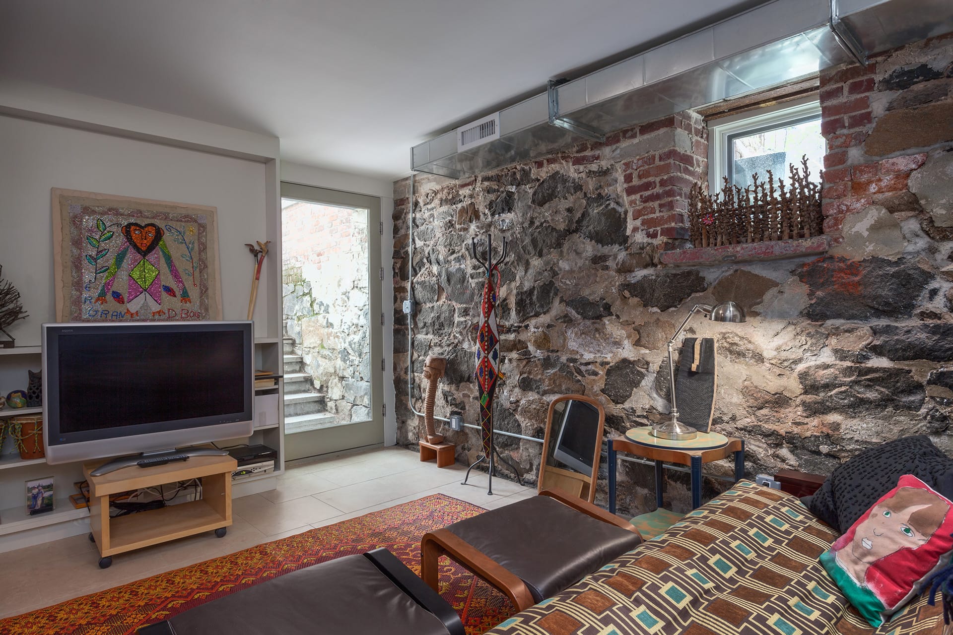 Basement level TV room with uncovered original fieldstone and an areaway leading out to the front yard.