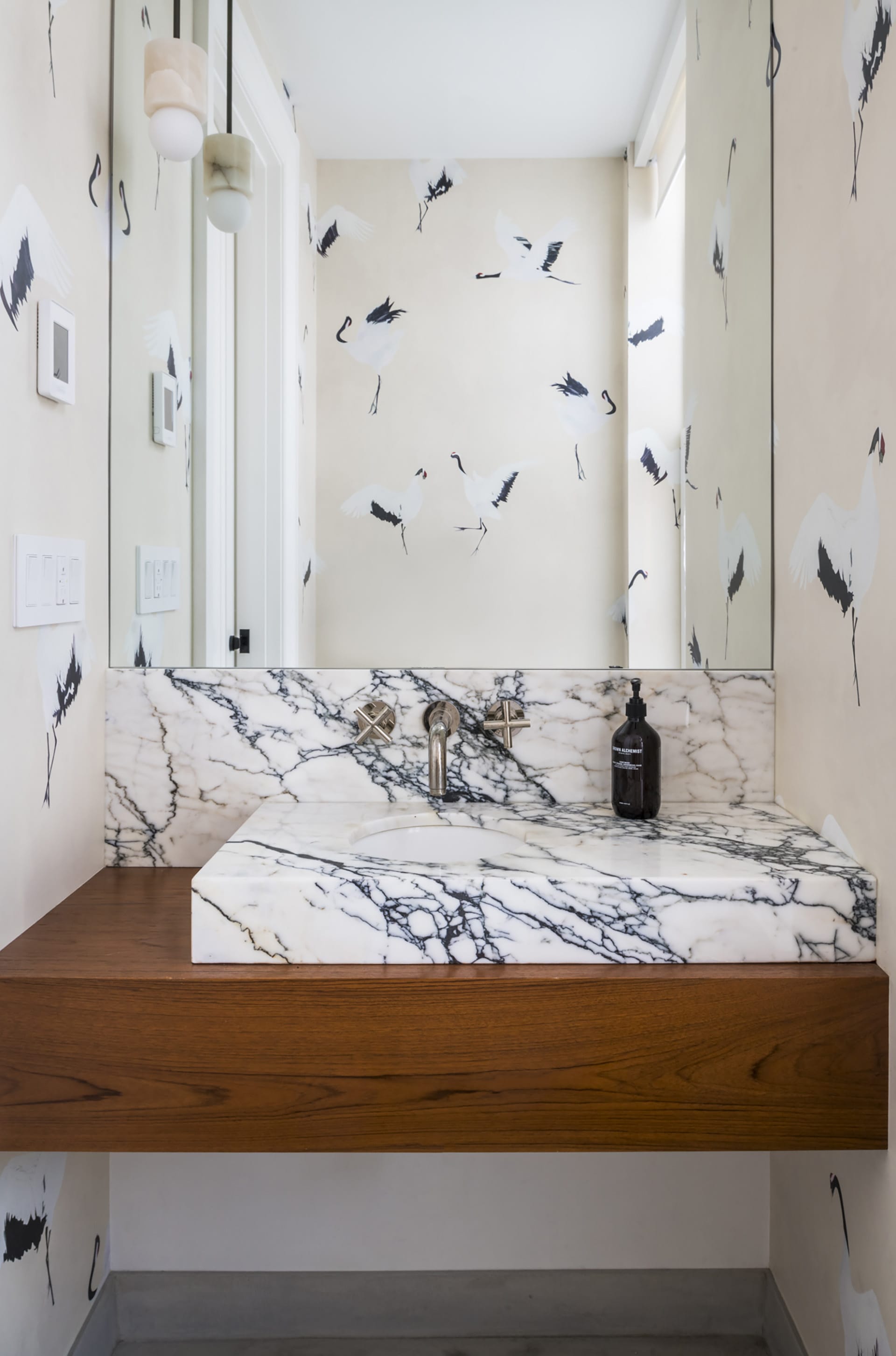 Powder room with a wood and marble vanity and wallpaper