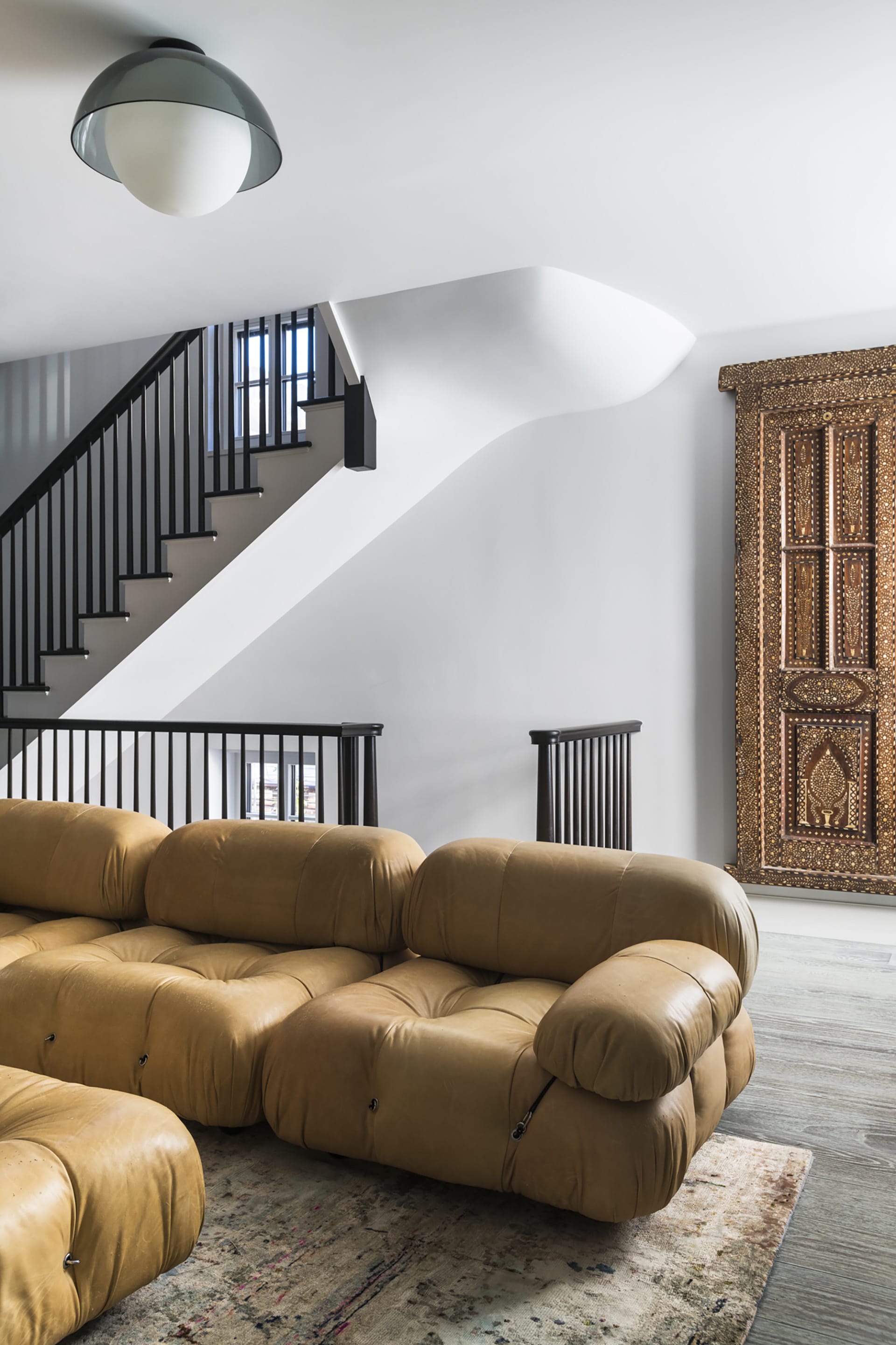 Living area with a Moroccan door, leather couch, and grey wood floors