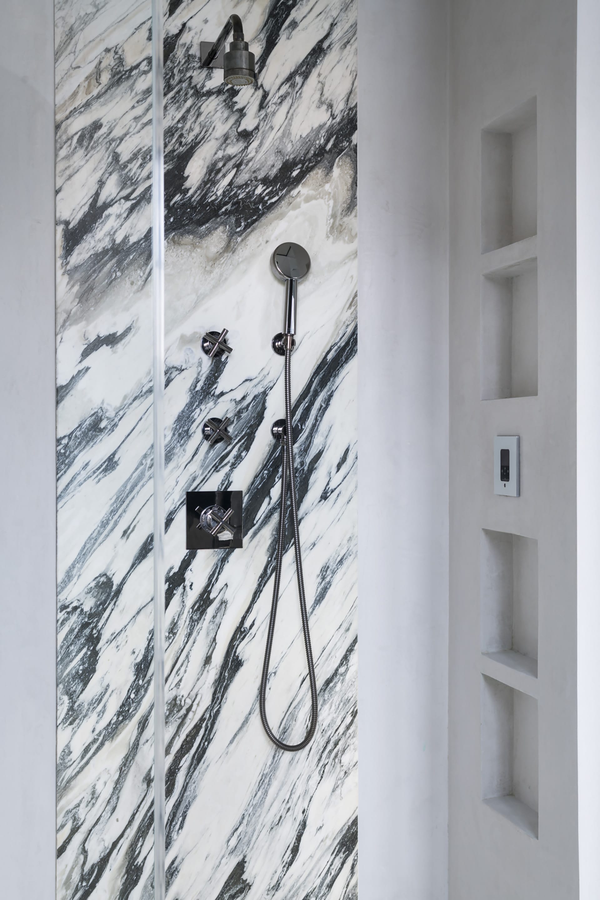 Primary bath with black and white marble wall in the shower.