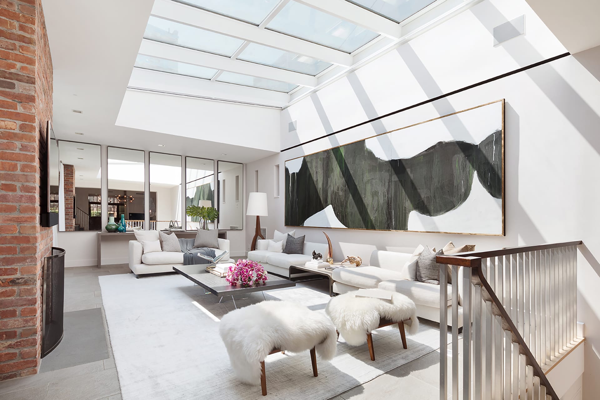 Living room with several large skylights, mirrors on the wall, and a large abstract painting