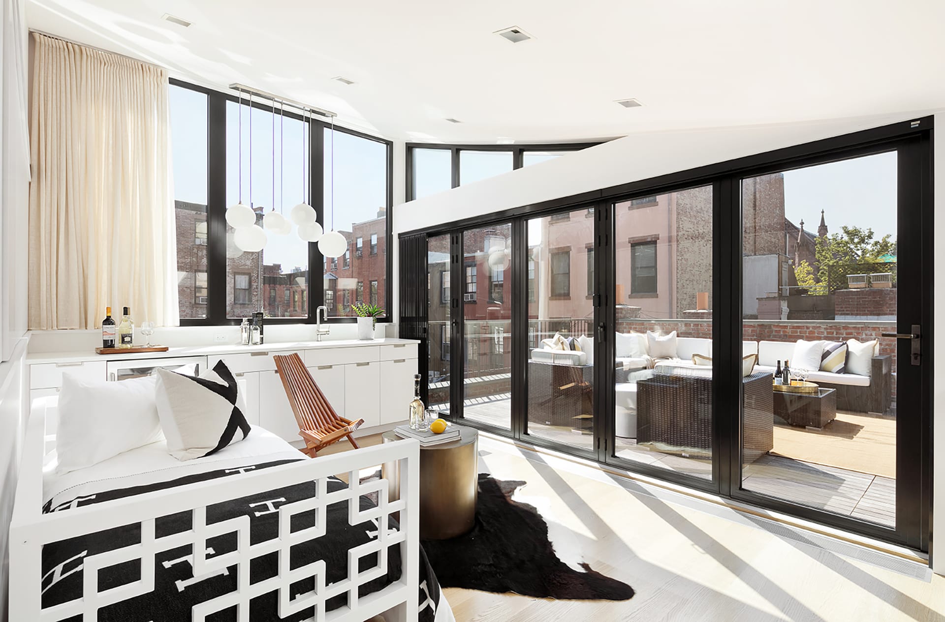 Penthouse with a curved ceiling and a large NanaWall sliding glass door system with outdoor furniture and a white daybed.