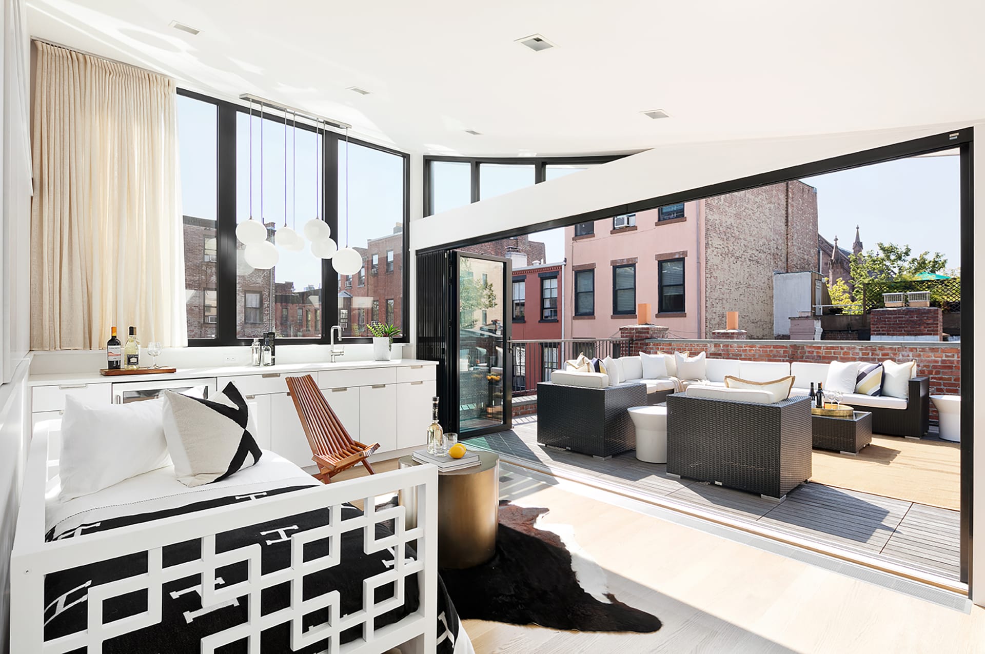 Penthouse with a curved ceiling and a large NanaWall sliding glass door system with outdoor furniture and a white daybed.