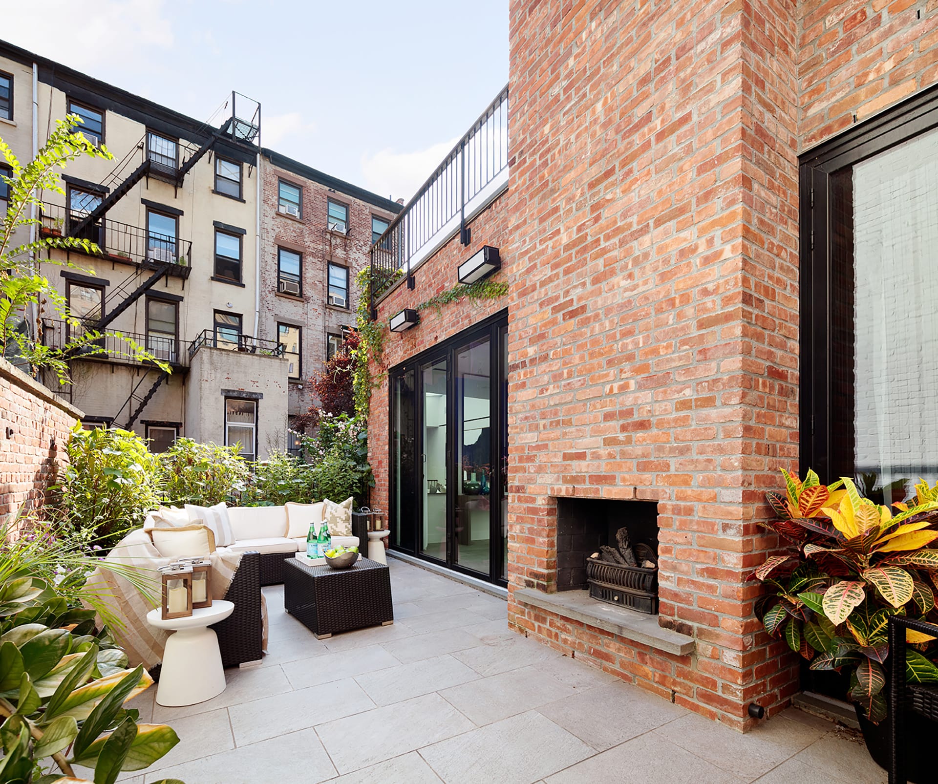 Rear yard of a Brooklyn Heights carriage house with outdoor furnishings and a brick fireplace