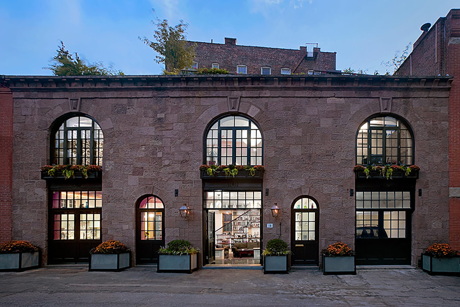 Front façade of a brownstone carriage house with large window openings.