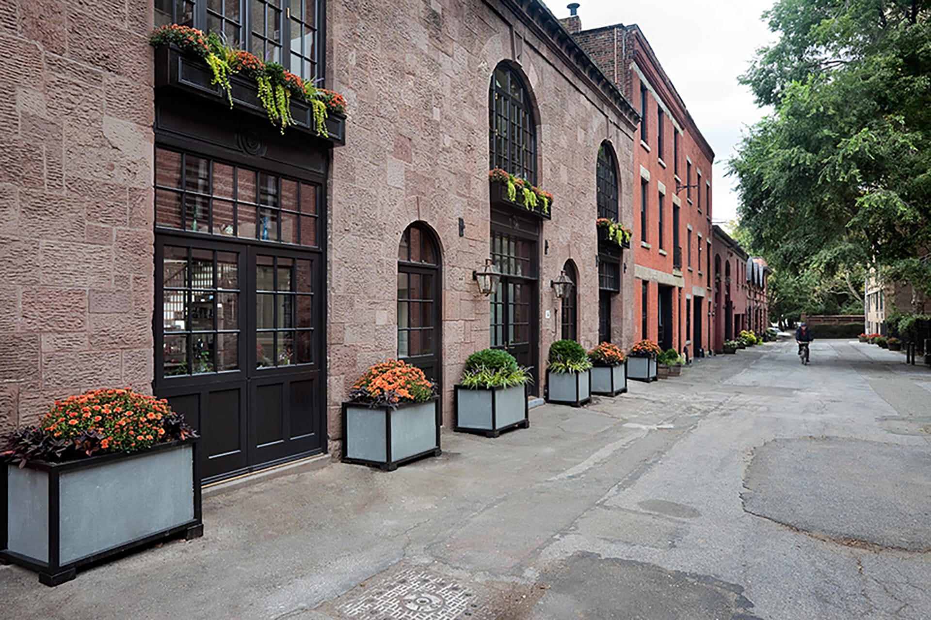 Front façade of a brownstone carriage house with large window openings.