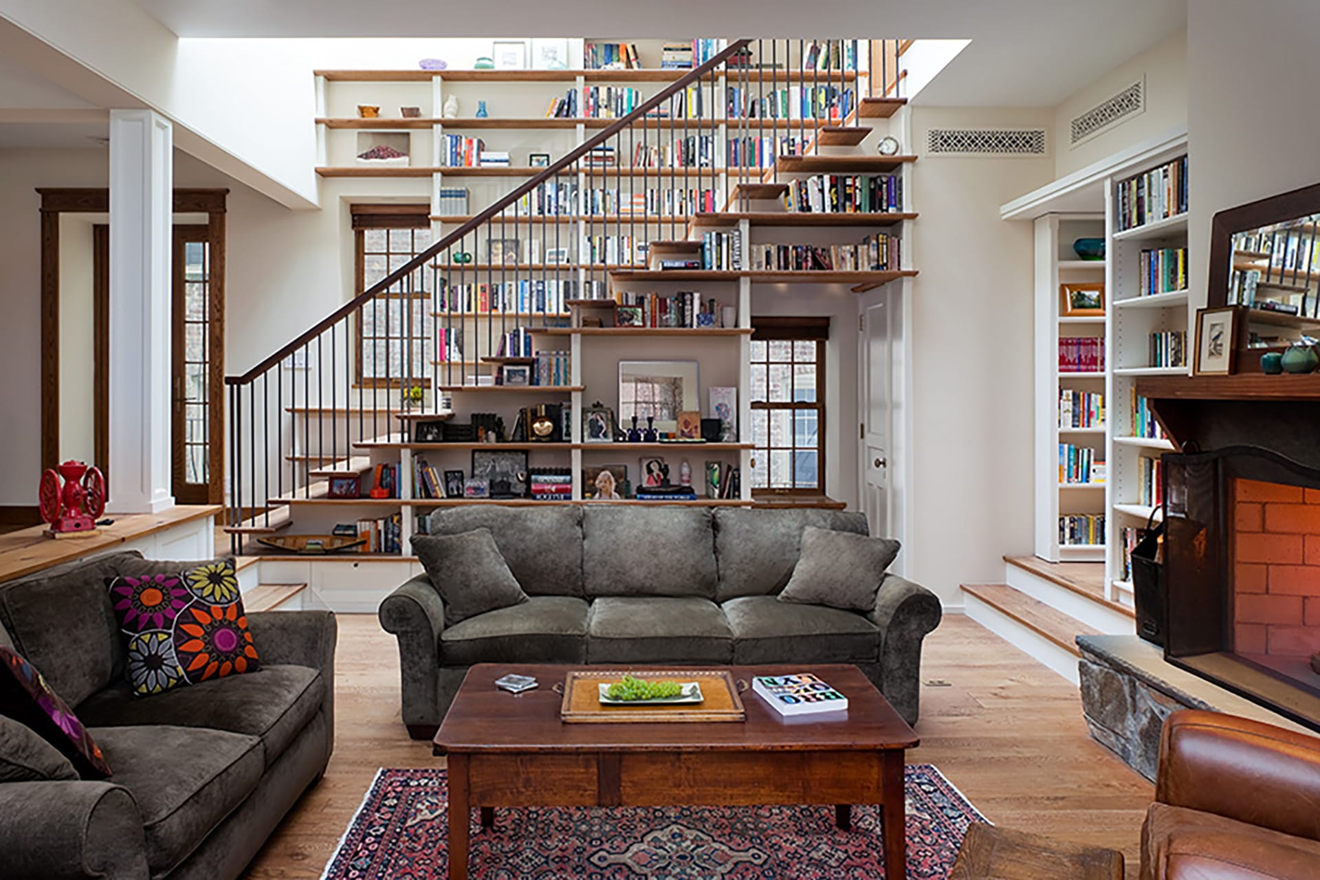 Living area in front of an open staircase lined with bookshelves.