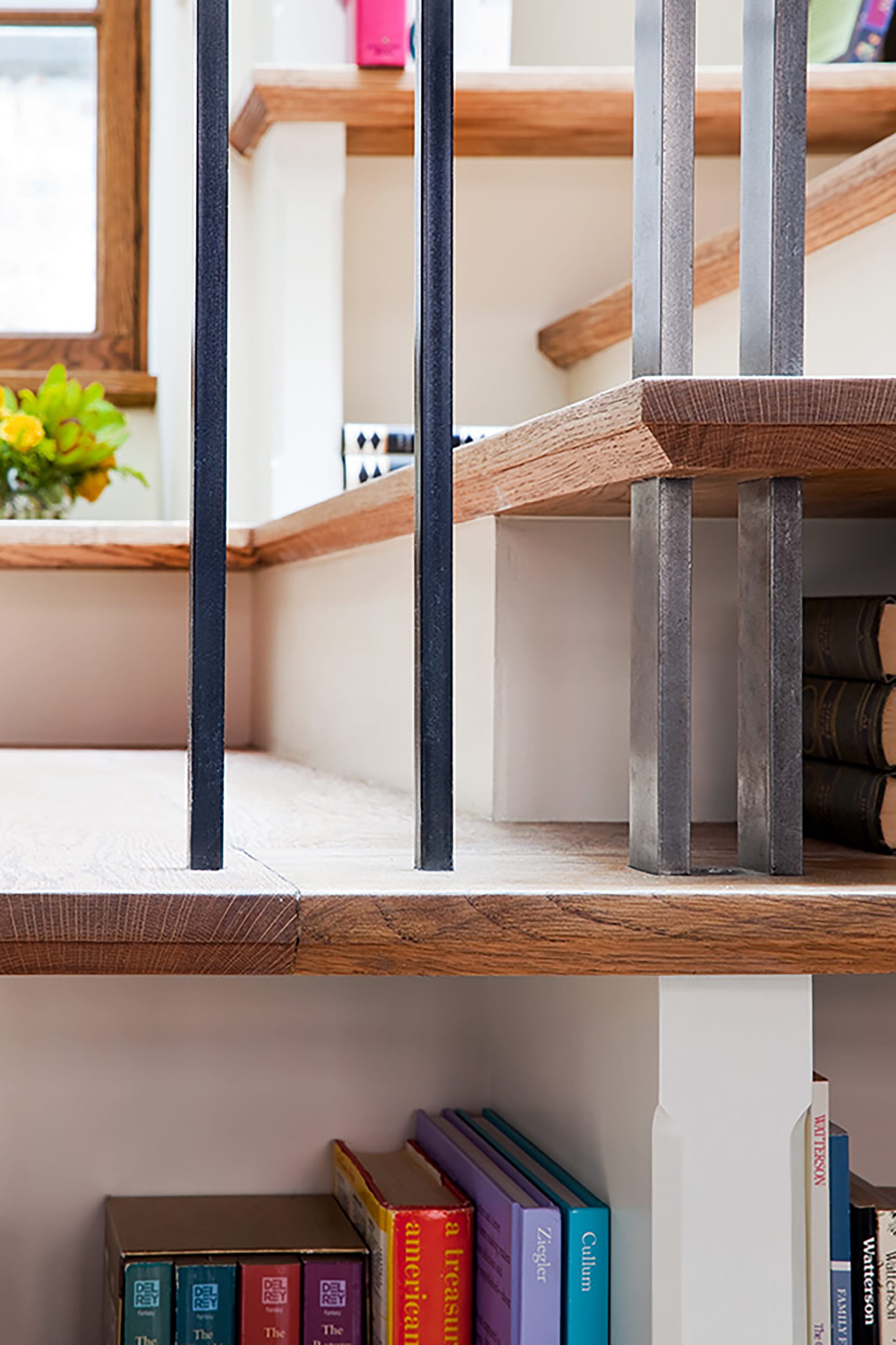 Detail of a staircase with built-in bookshelves and metal balusters