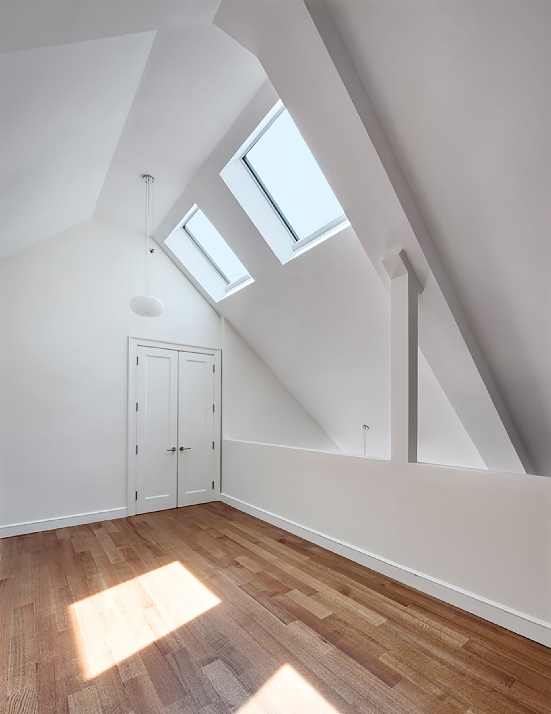 Loft-style condo unit with white walls, a pointed ceiling, and wood floors