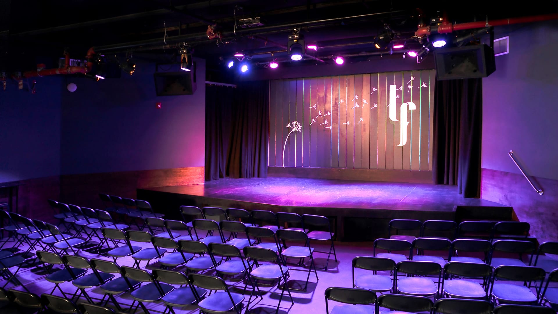 Stage at Littlefield with purple lights and rows of folding chairs.