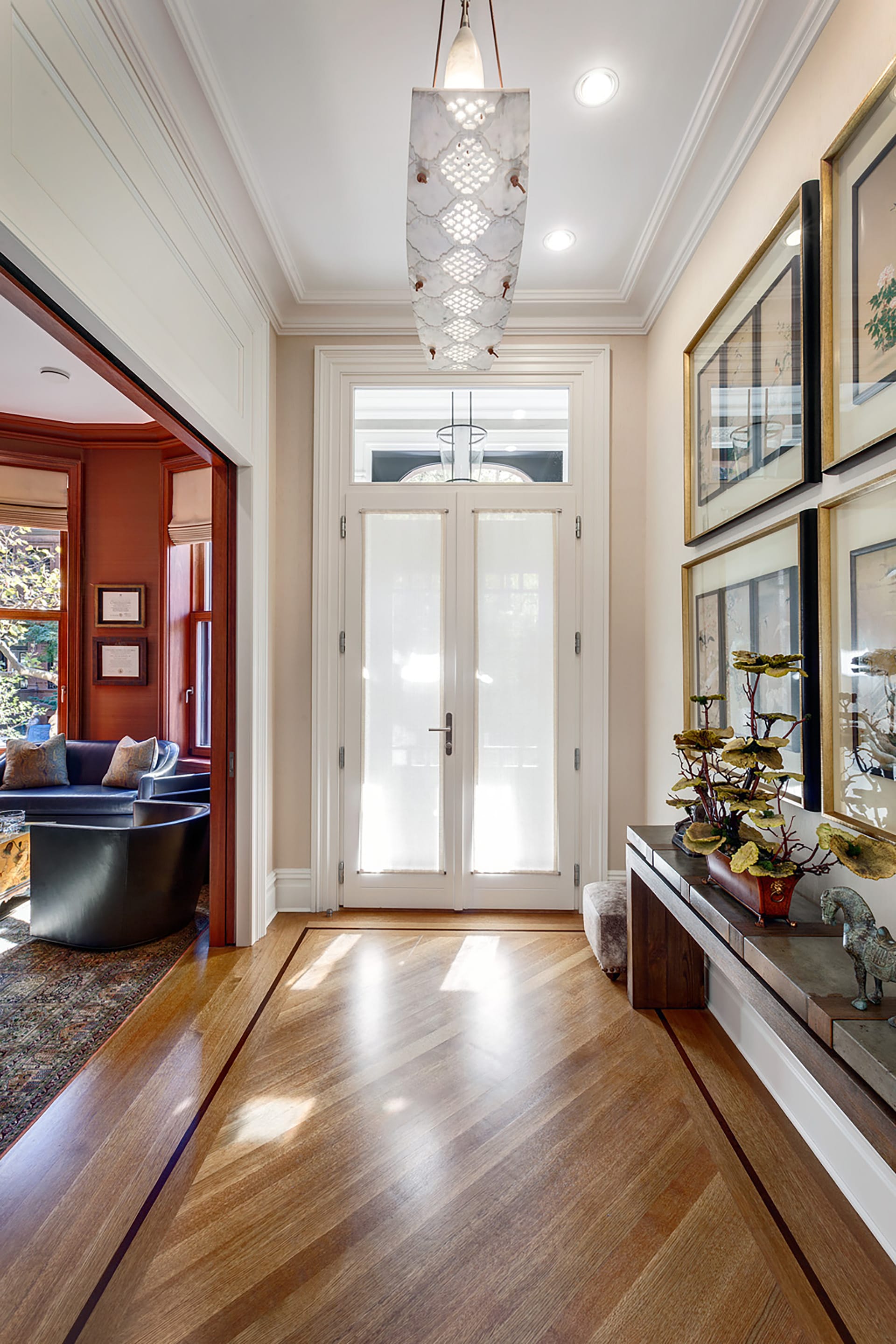 Restored entryway with new vestibule, white molding detail and a large decorative light fixture