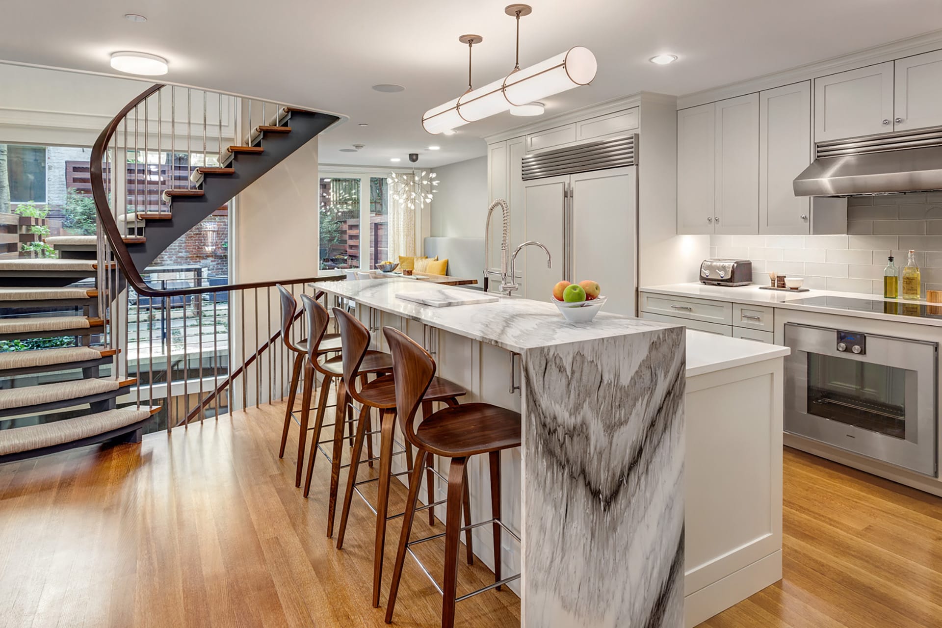 Kitchen with marble island, sculptural staircase, and white cabinetry