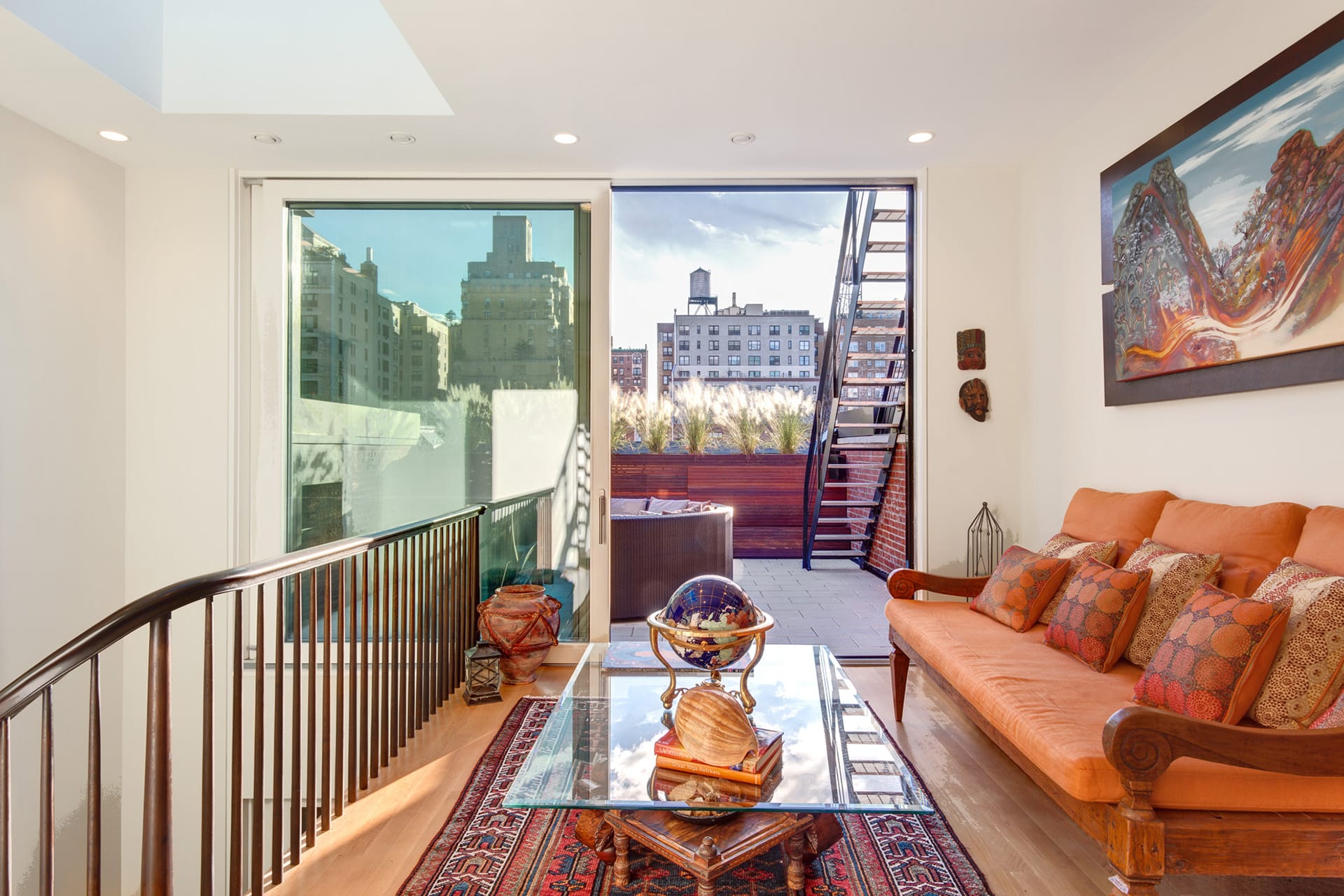 Top-floor seating area with an orange couch and large sliding glass door leading out to the roof deck