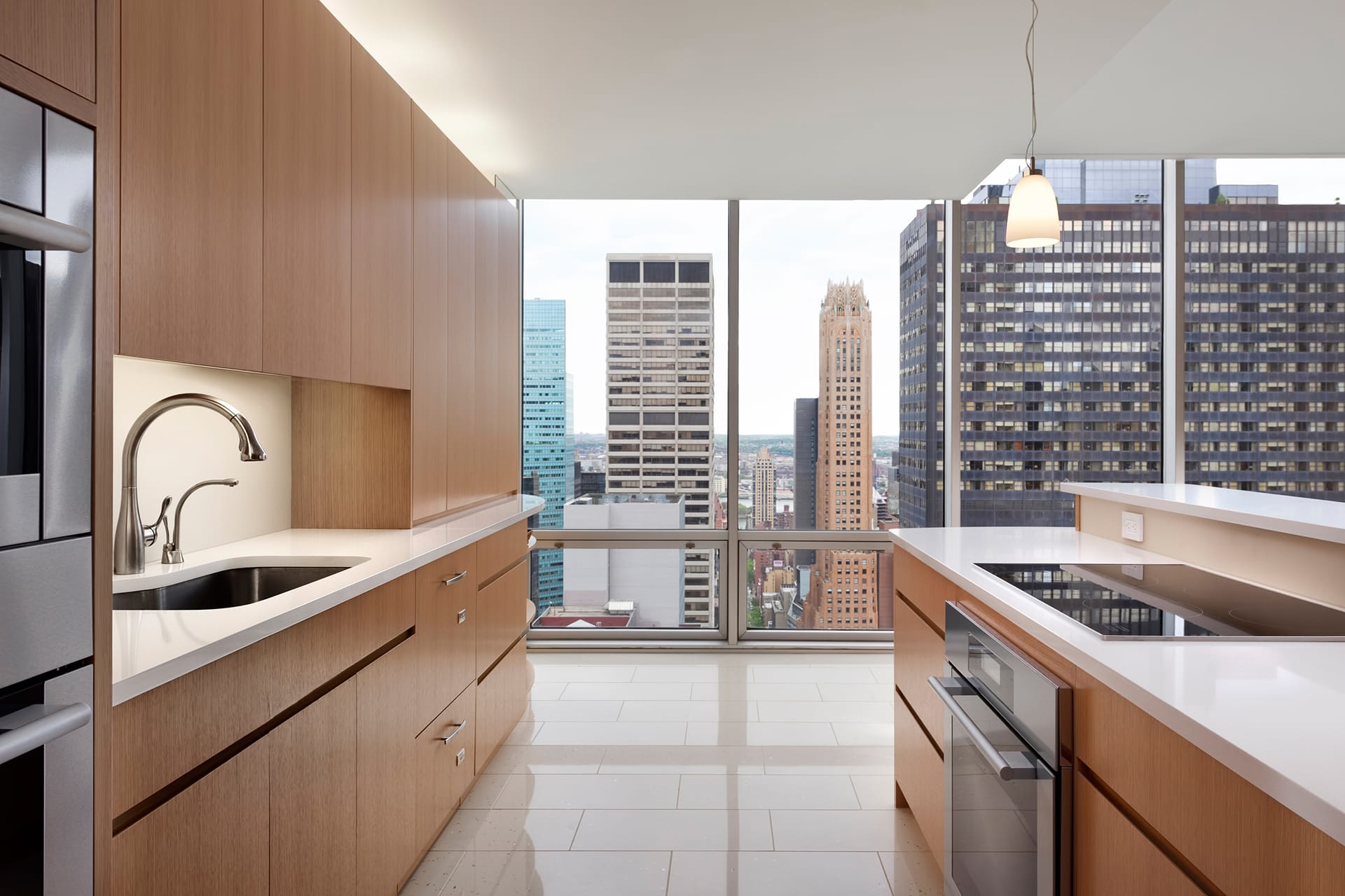 Kitchen with a white island, large floor tiles, and light wood cabinetry.