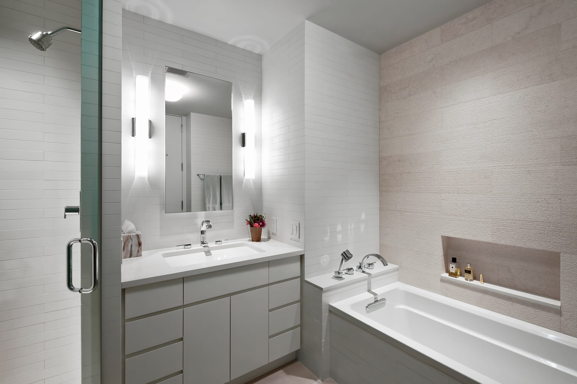 Primary bathroom with a built-in bathtub on the right, separate shower stall on the left, and all-white vanity in the center.