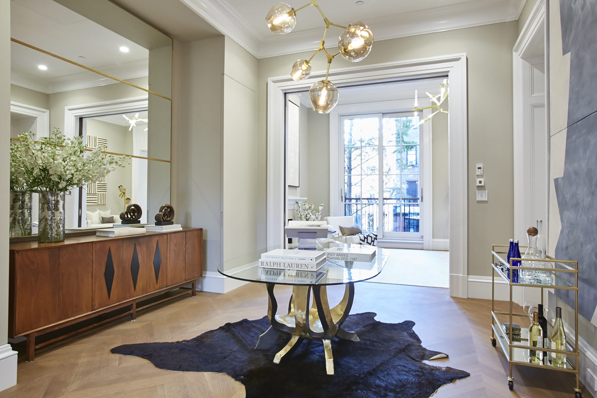 Living space in a Brooklyn Heights Passive House with Chandelier, credenza, bar cart, and glass table.