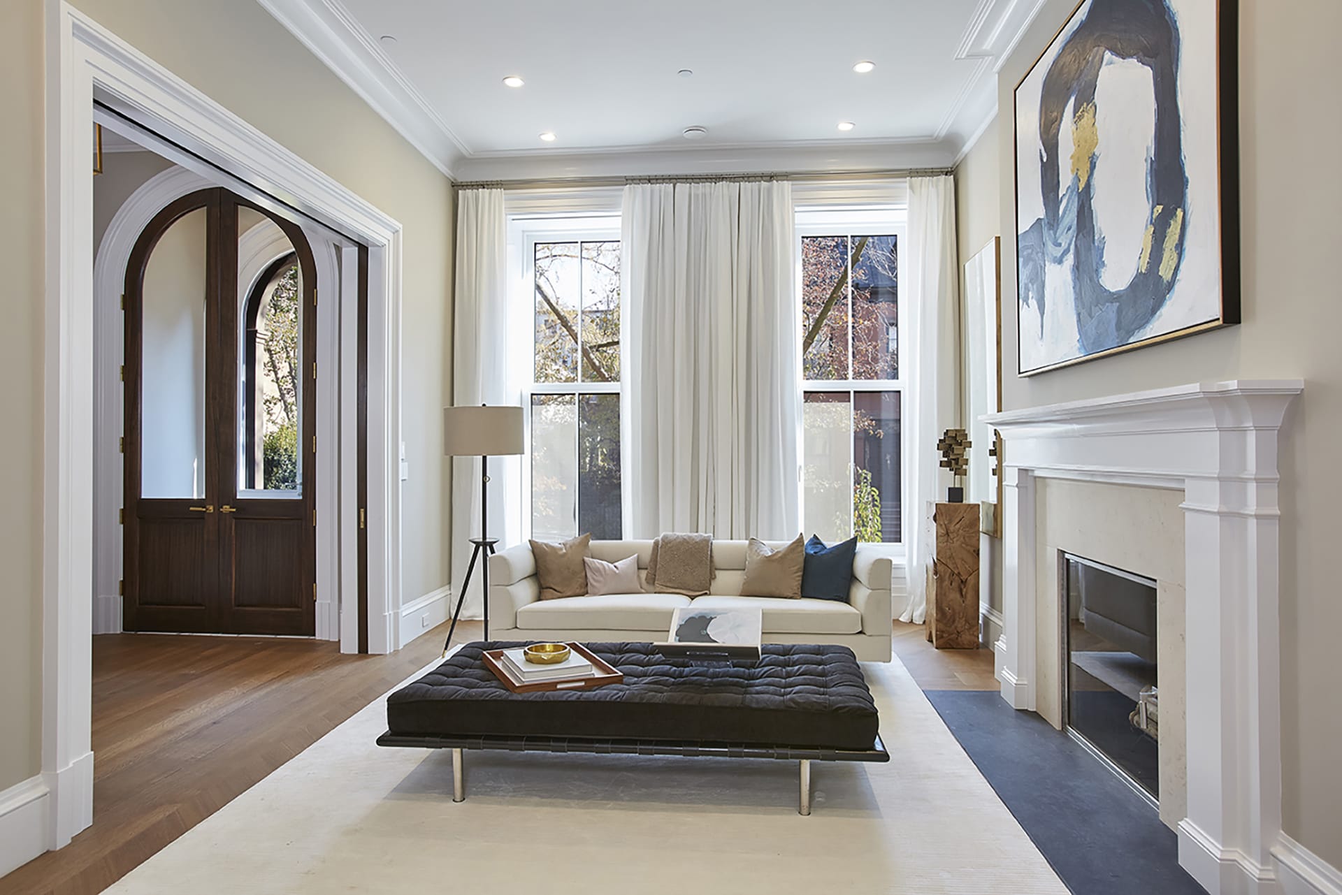 Living room and entryway of a Brooklyn Heights Passive House with arched historic doors and electric fireplace.