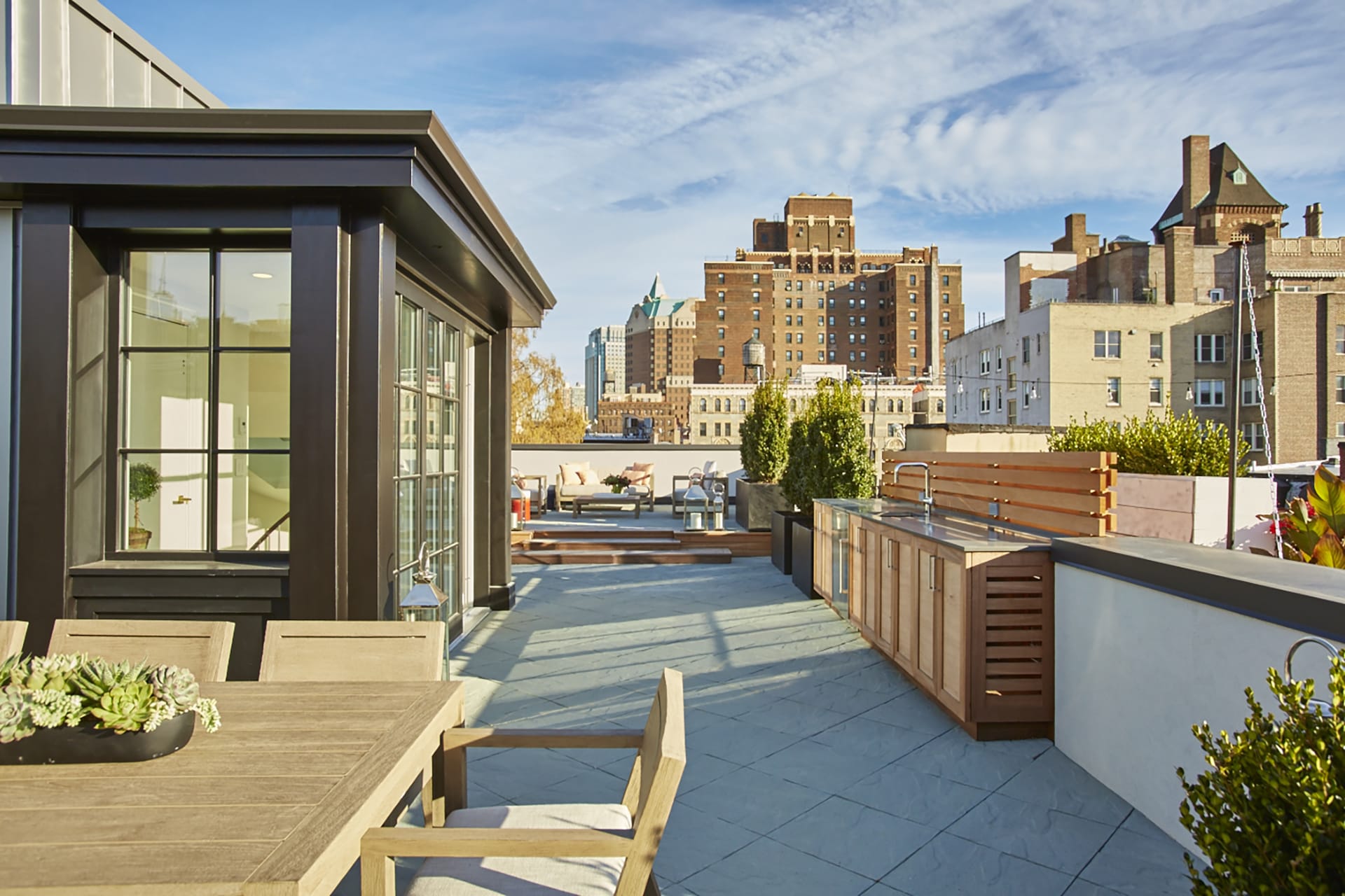 Rooftop with glazed bulkhead, outdoor kitchen, and bluestone pavers on a Brooklyn Heights Passive House.
